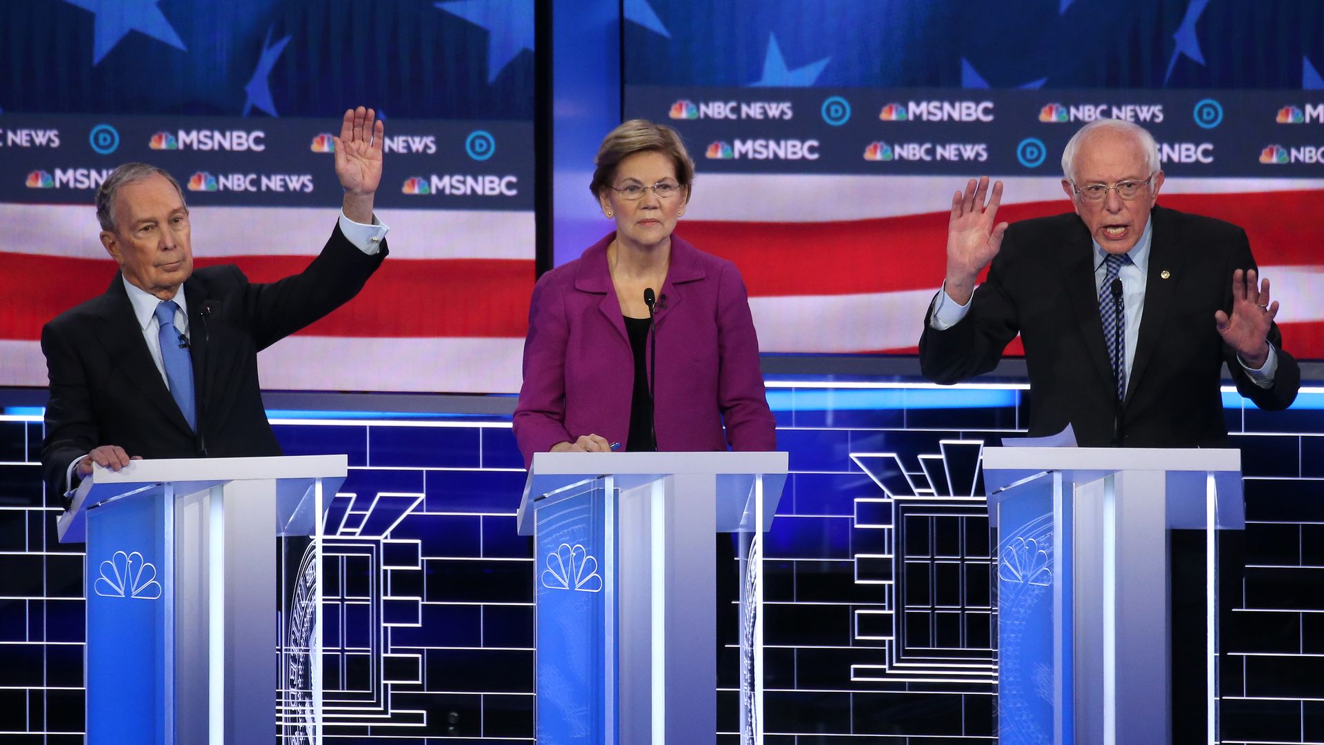 Bernie Sanders gestures while Mike Bloomberg raises his hand at the Democratic Las Vegas debate