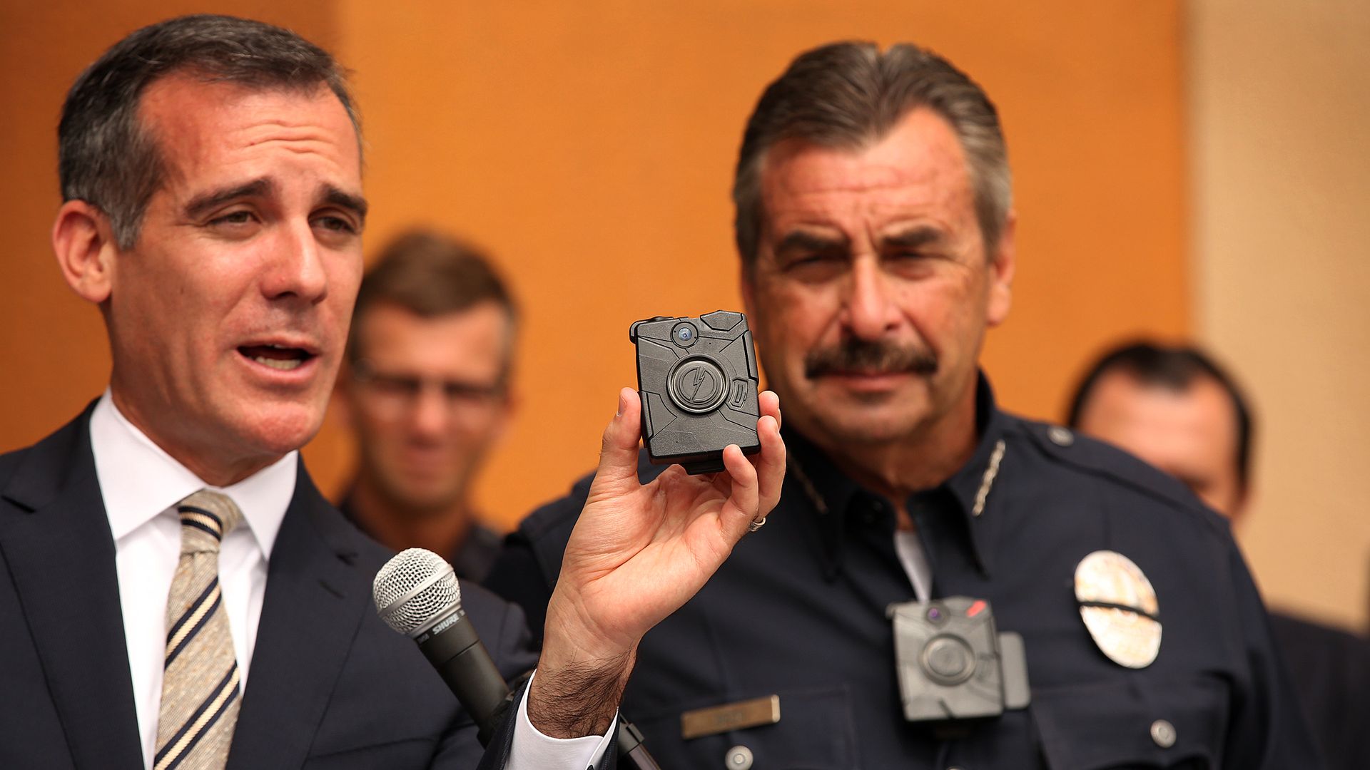 Los Angeles Mayor Eric Garcetti, left, with LAPD Chief Charlie Beck, right, who is wearing a body camera, shows the new LAPD body camera and cell phone with special ap's that allow the officer to see what the camera is recording, during a press conference.