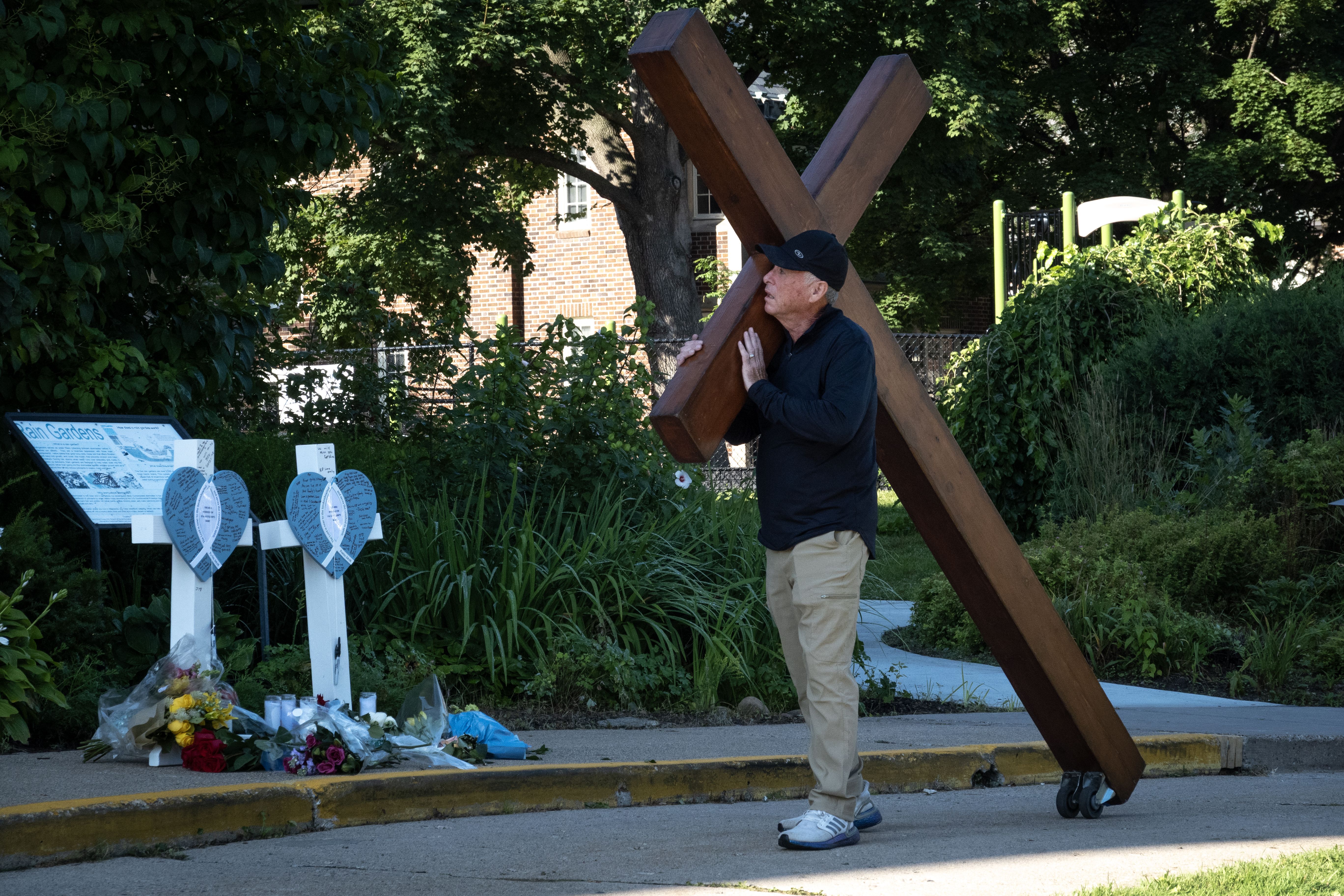 A man carries a large cross to a memorial