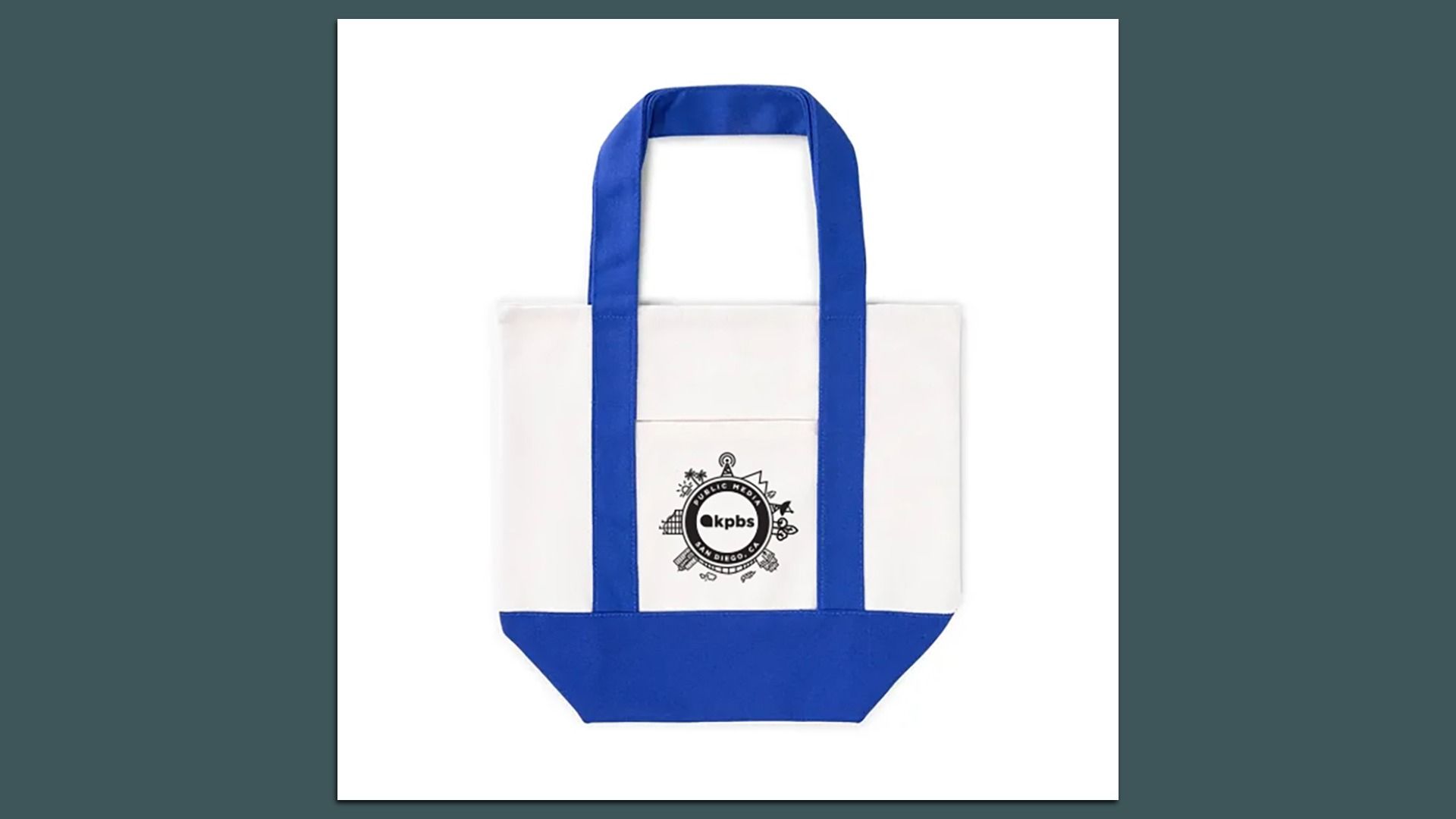White canvas tote bag with blue handles and bottom. Features a small front pocket with a black circular ‘‘kpbs Public Media San Diego, CA’’ logo surrounded by small icons.