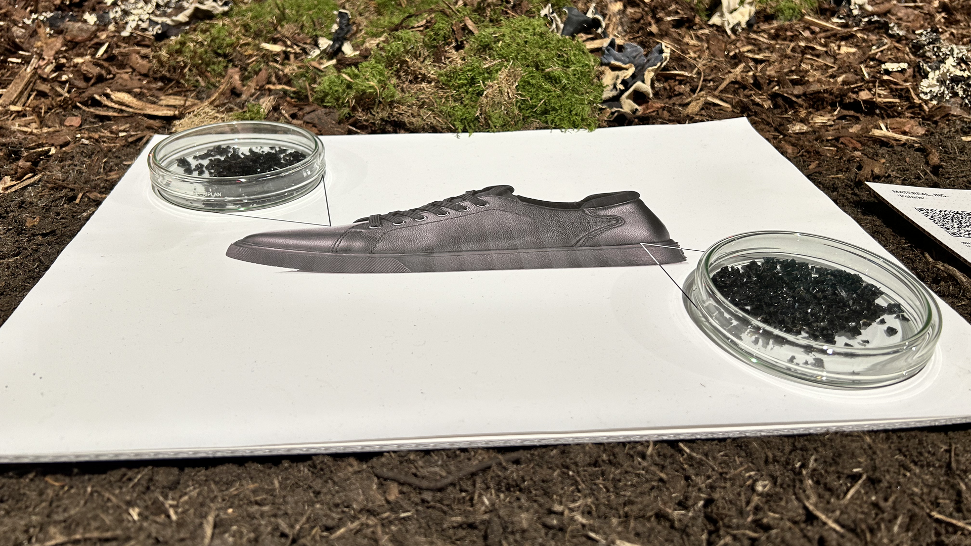 A photo shows two petri dishes filled with Matereal's "Polaris" material, which resembles black pellets. The dishes sit on posterboard with a drawing of a men's dress shoe. 
