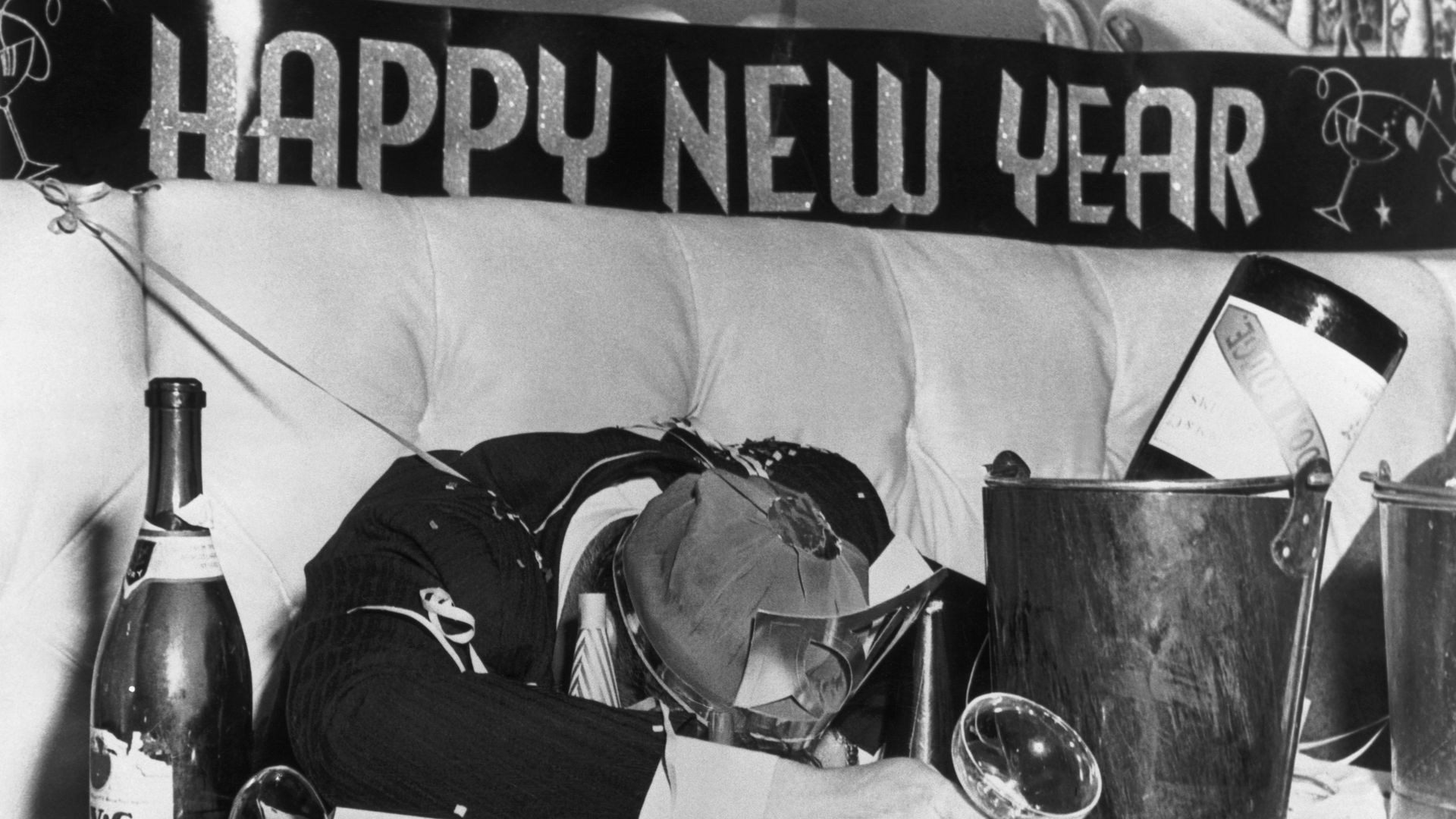 A man is passed out on his face under a Happy New Year banner 