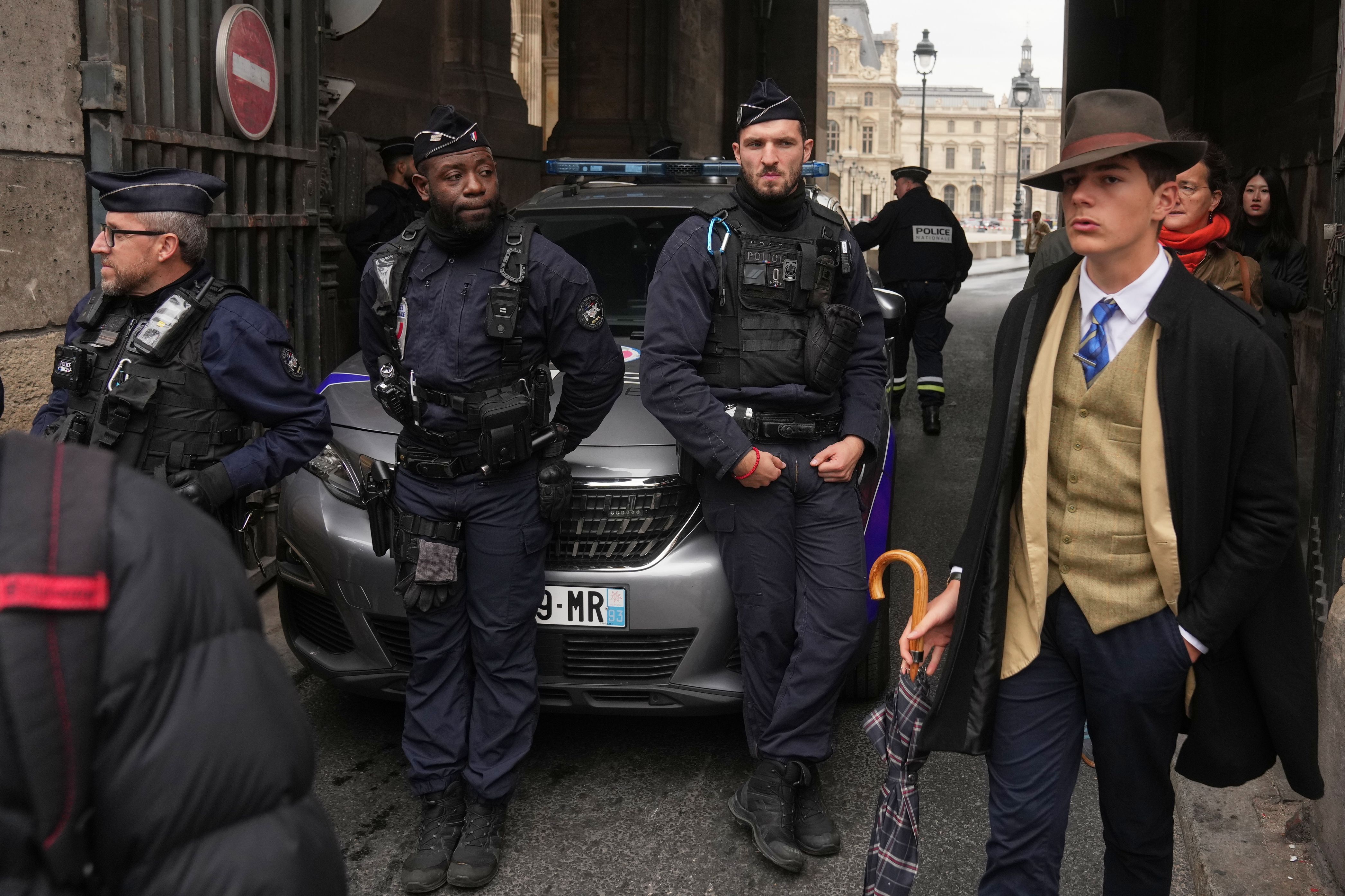 Pedro Elias Garzon Delvaux, right, walks past as police officers block an entrance to the Louvre after thieves carried out a daylight raid on French crown jewels, in Paris, Oct. 19, 2025. (AP Photo/Thibault Camus, File)
