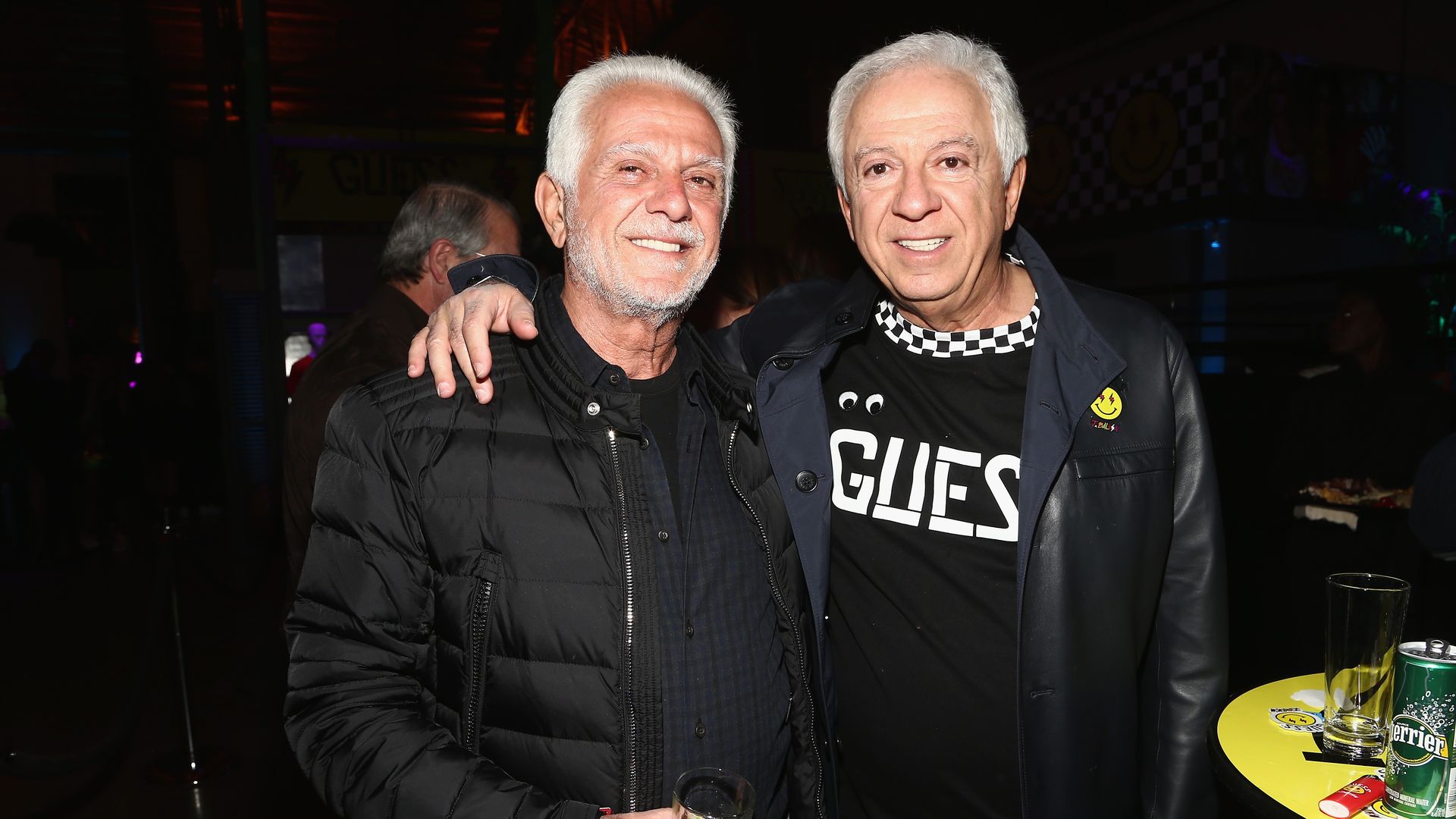 Guess co-founders and brother Maurice and Paul Marciano, dressed in black, pose together for the camera at a party in Los Angeles.