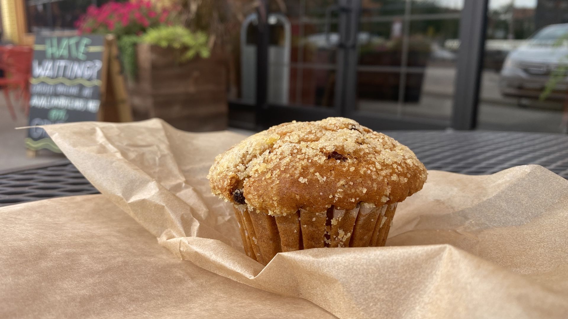 A pumpkin muffin with raisins sits on an outdoor table.