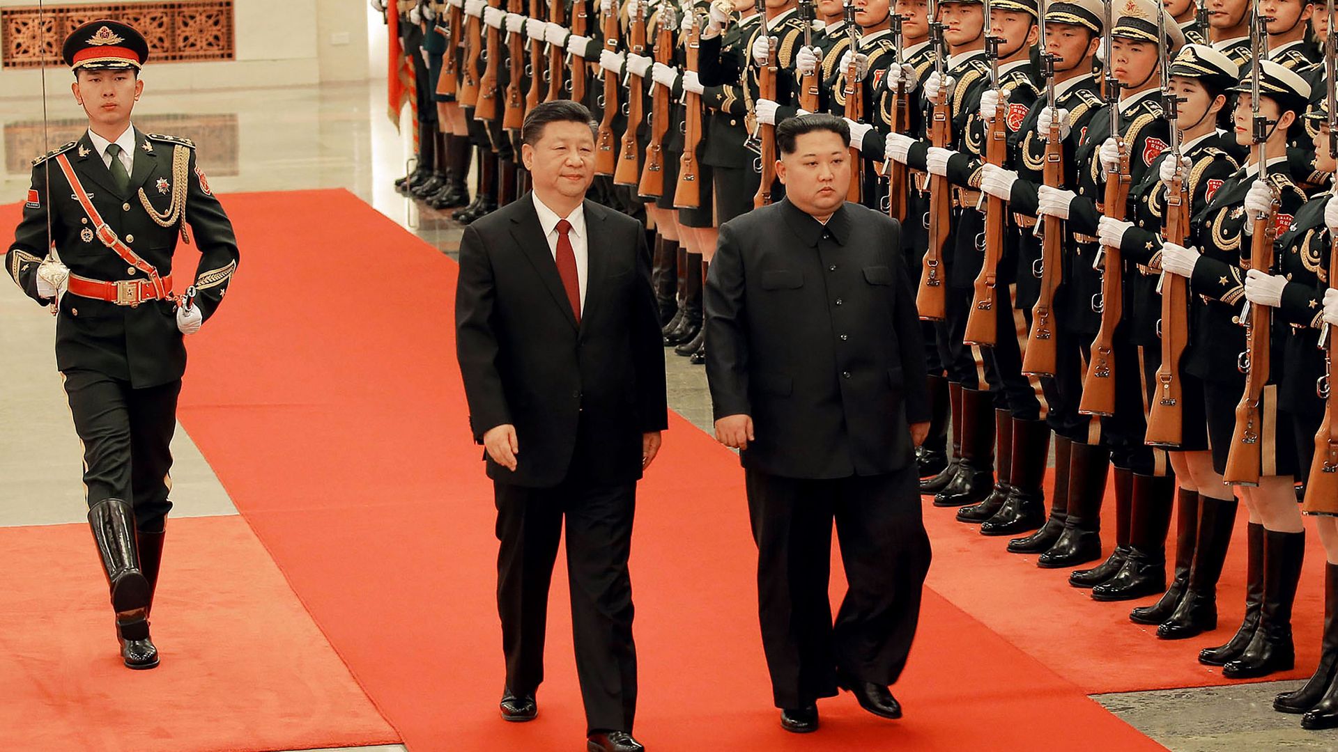 Chinese President Xi and North Korean Leader Kim march down red carpet next to line of soldiers together during their surprise meeting in Beijing