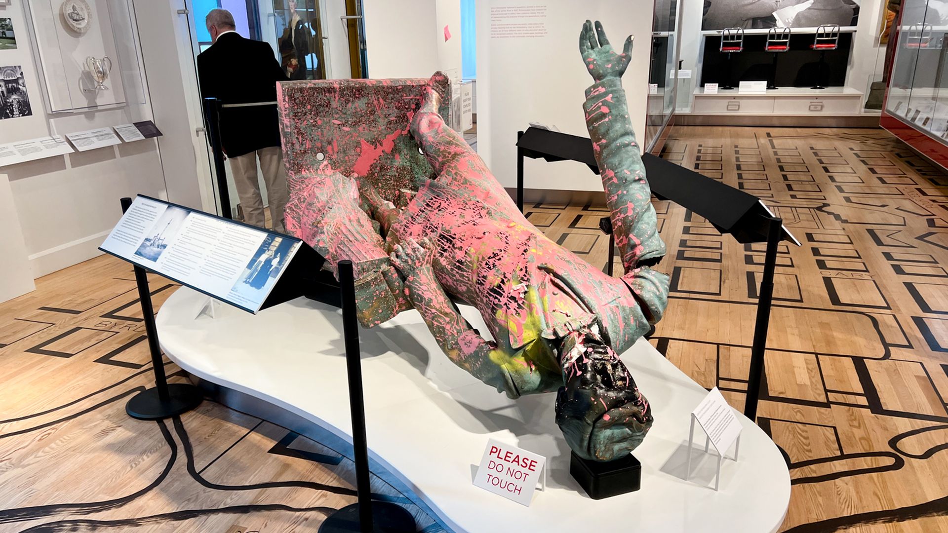 A photo of a statue of Jefferson Davis laying on its back, broken and covered with pink paint.