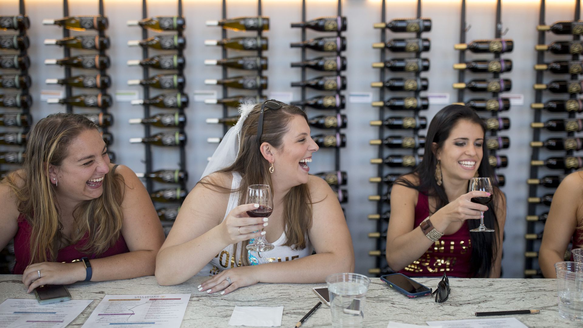 Women drink wine at a bar during a bachelorette party