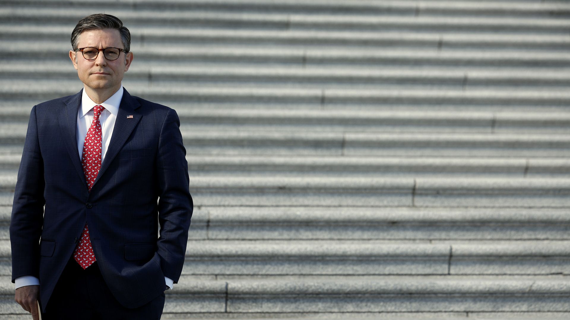 House Speaker Mike Johnson stands on the Capitol steps.