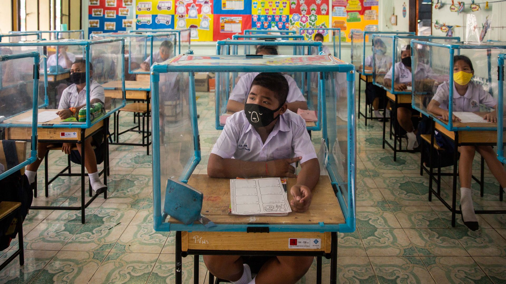  Thai students wear face masks and sit at desks with plastic screens used for social distancing at the Wat Khlong Toey School on August 10, 2020 in Bangkok, Thailand. 
