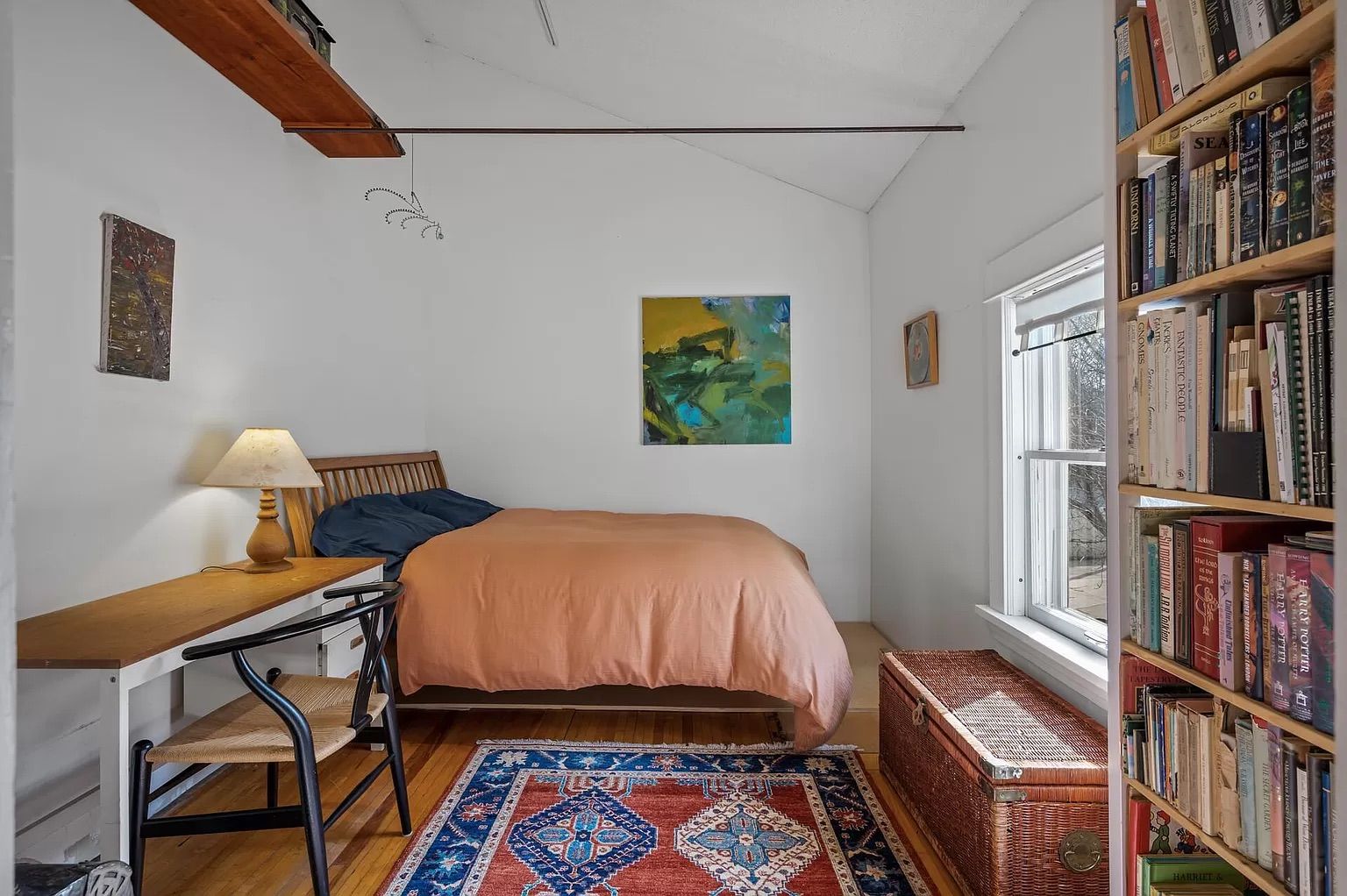 A bedroom with white walls and colorful furniture.
