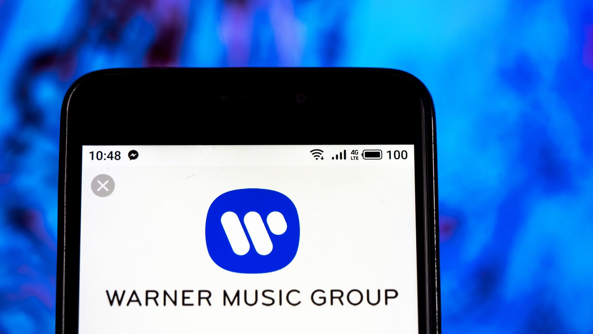 In this image, Warner Music Group logo is displayed on an iphone.