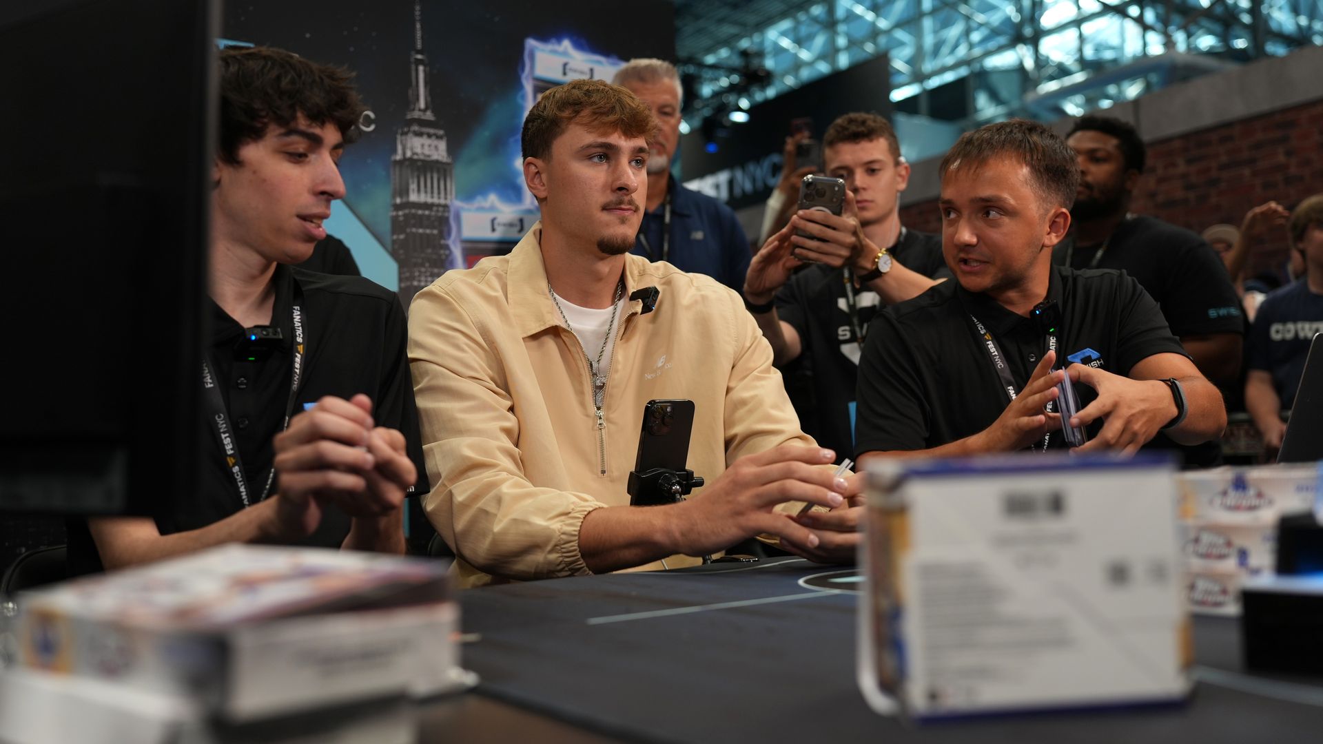 Cooper Flagg sits on a table with people around him.