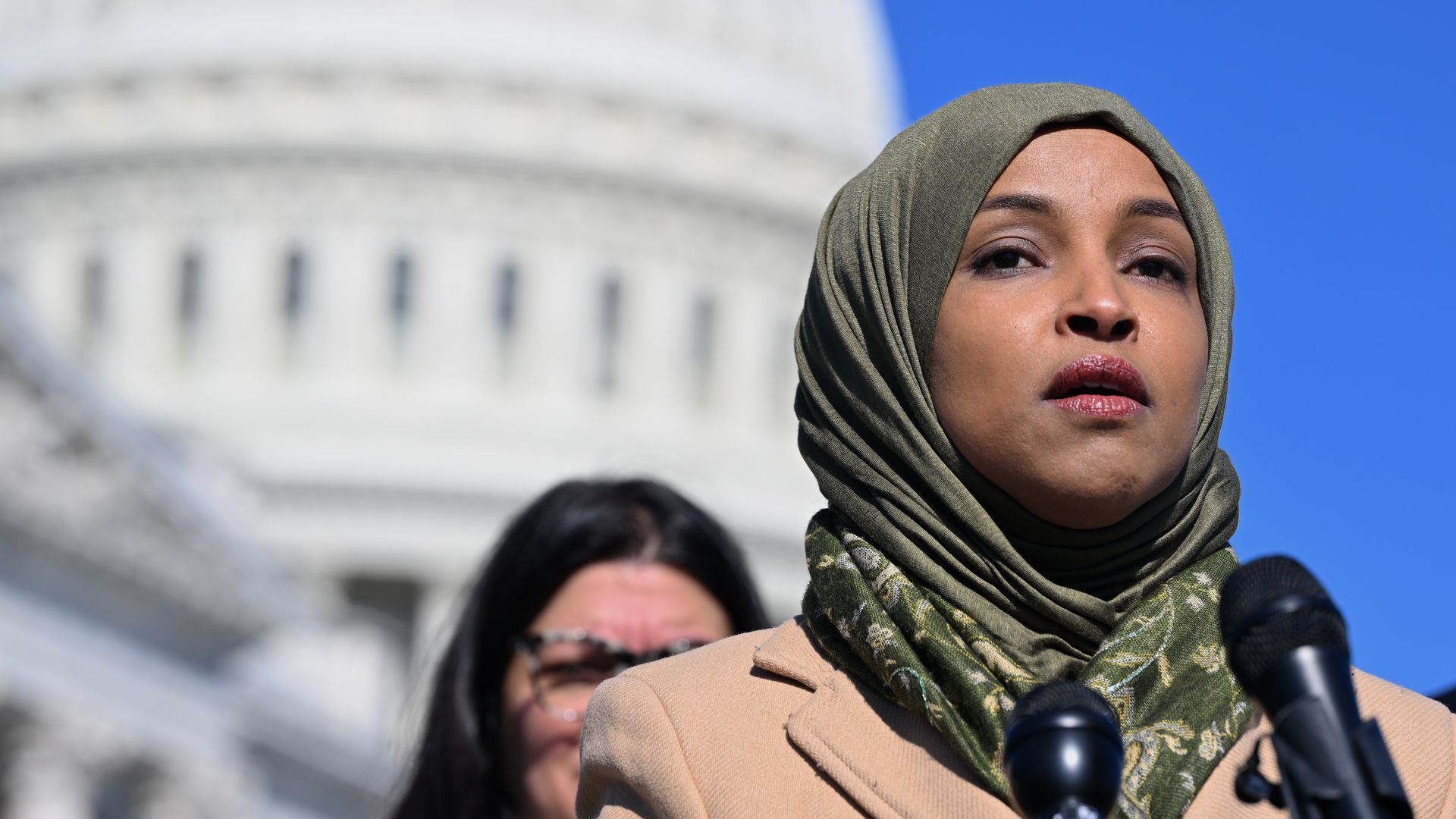 Rep. Ilhan Omar, wearing a beige jacket and green hijab.