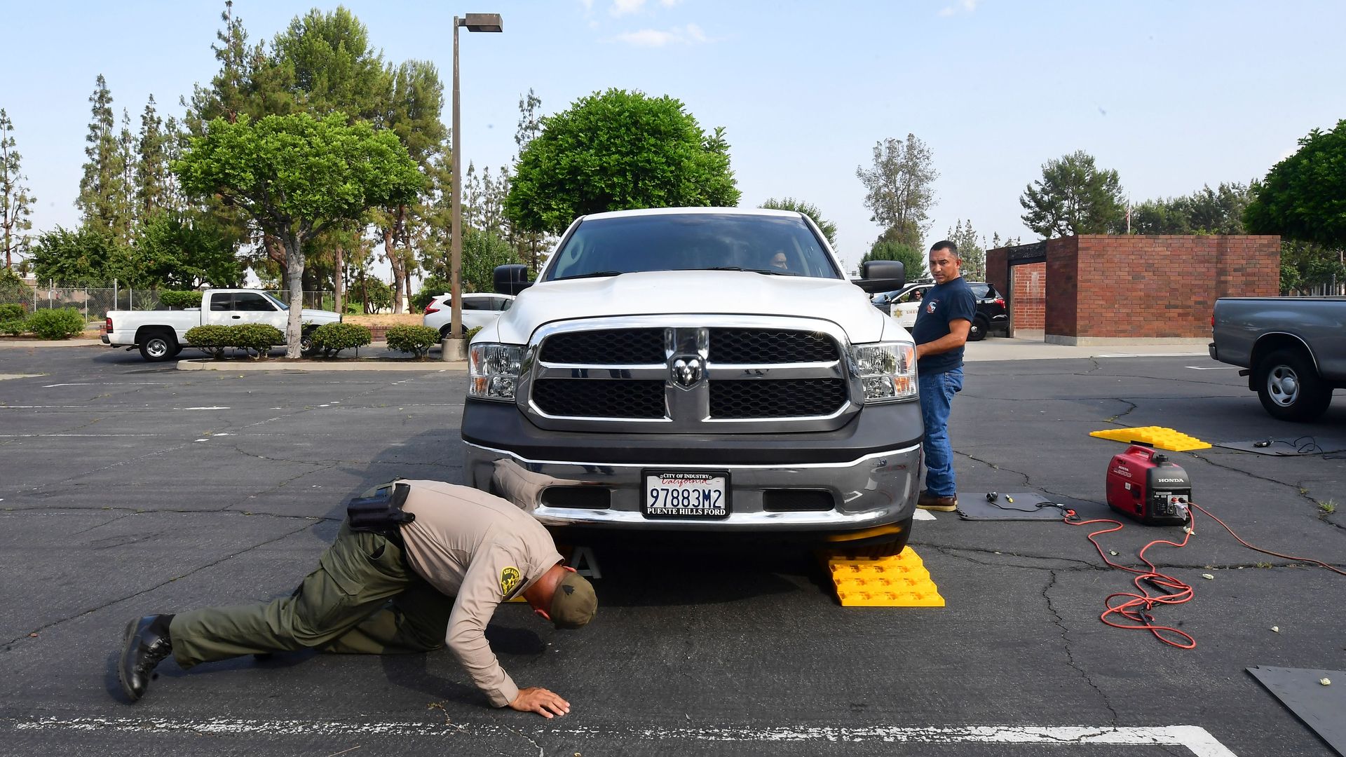 Image of a police officer looking under a pickup truck for the catalytic converter. 