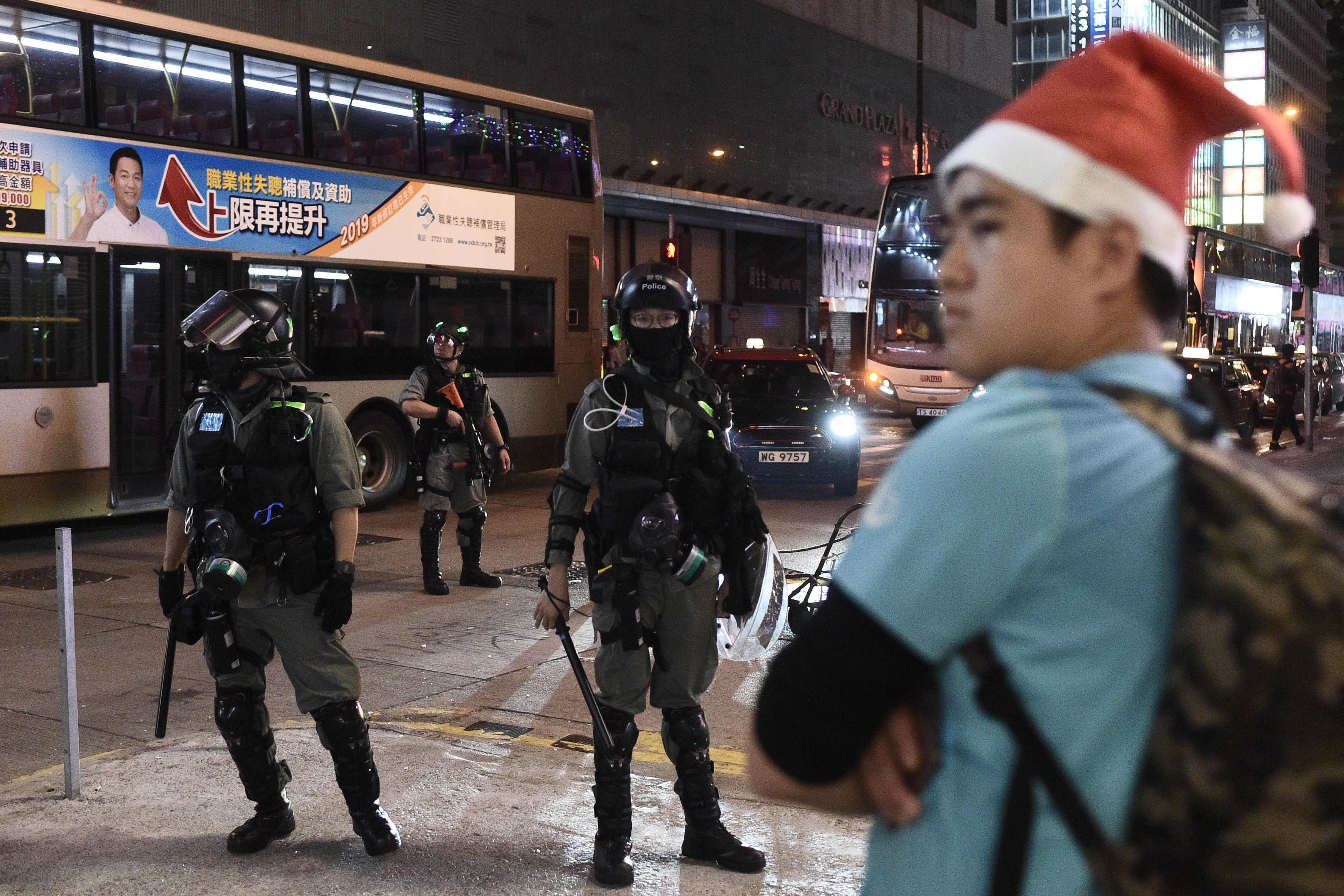 A man with a Santa hat stands in front of riot police during a protest in Mong Kok district in Hong Kong on December 25