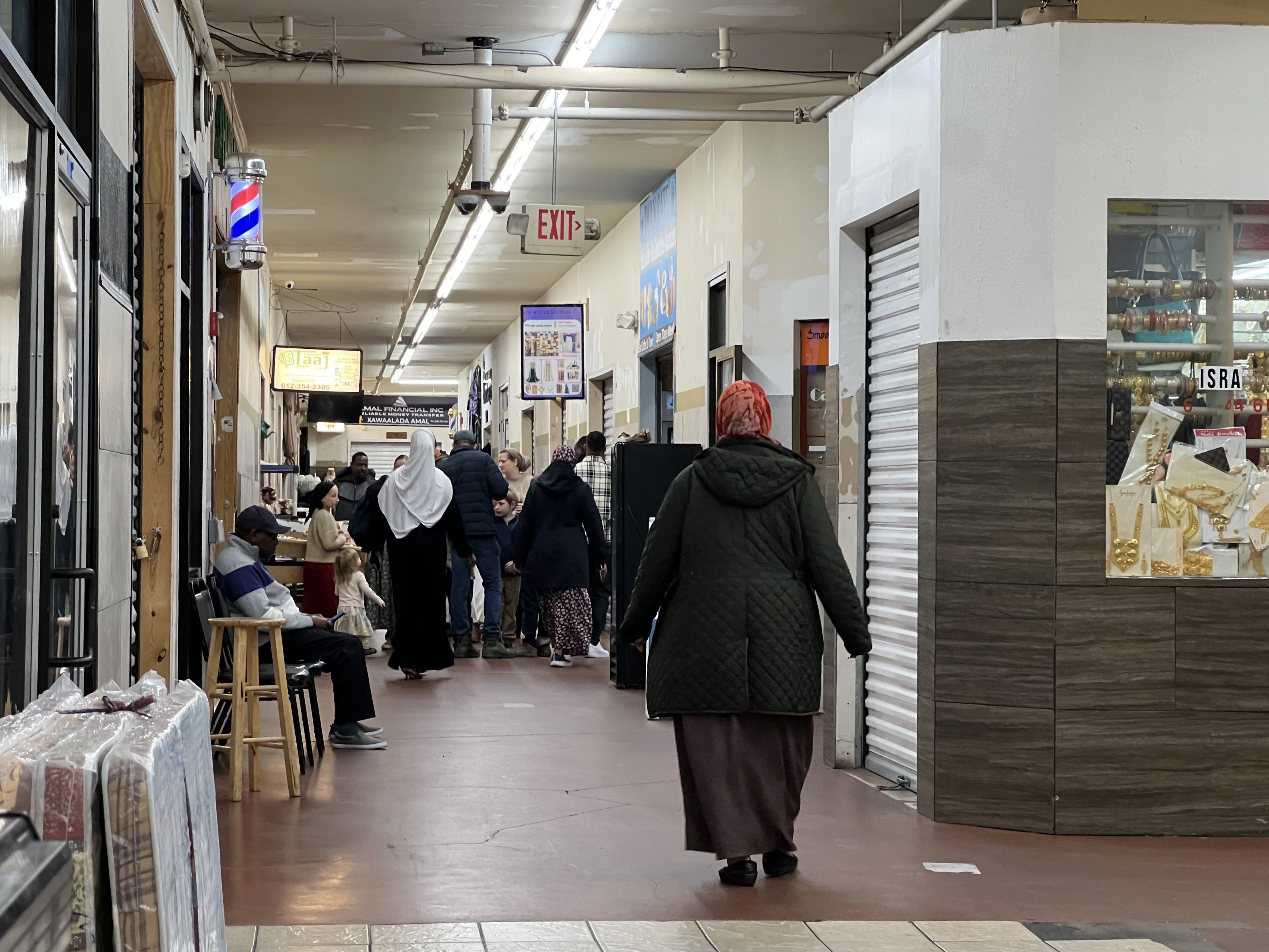 People walk down a narrow hallway in an indoor shopping mall