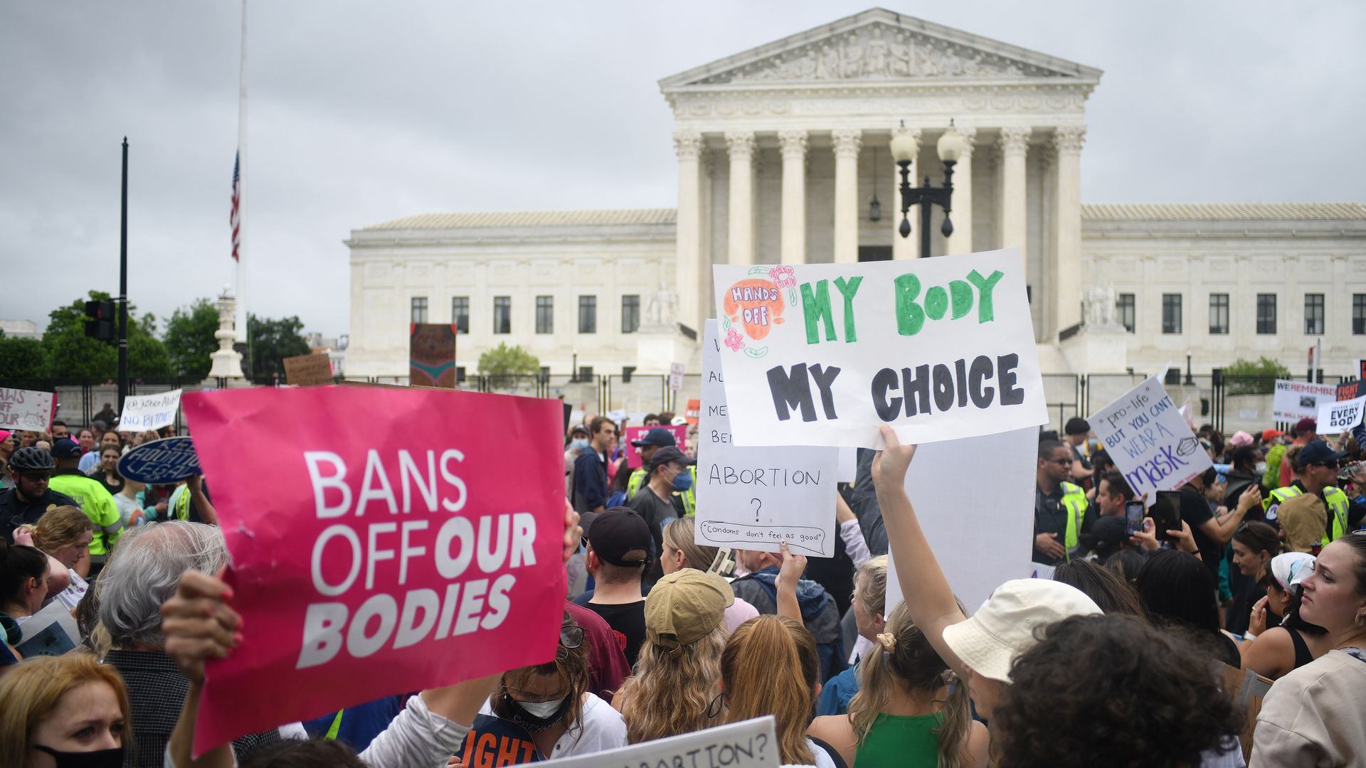 Picture of signs that say "bans off our bodies" and "my body my choice" being held up in front of the Supreme Court