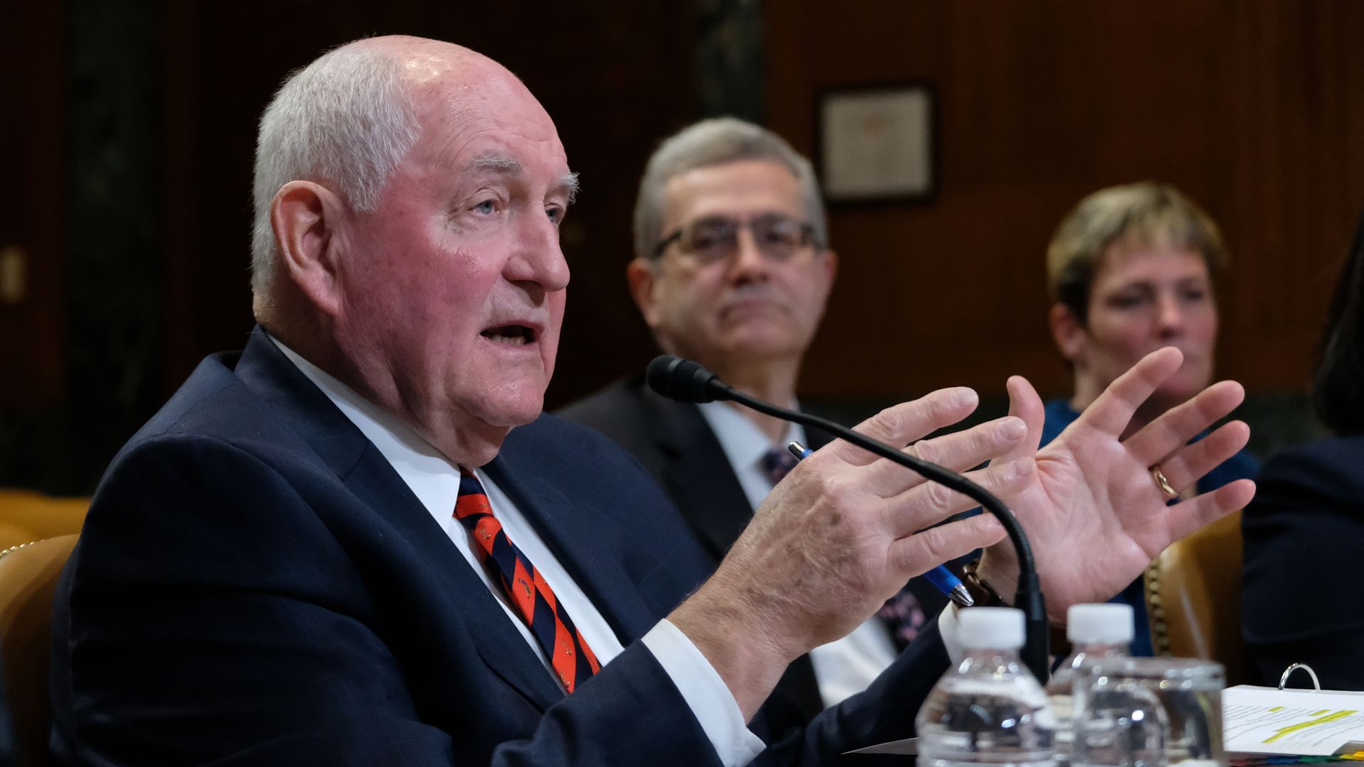 Sonny Perdue sitting and talking into a microphone. 
