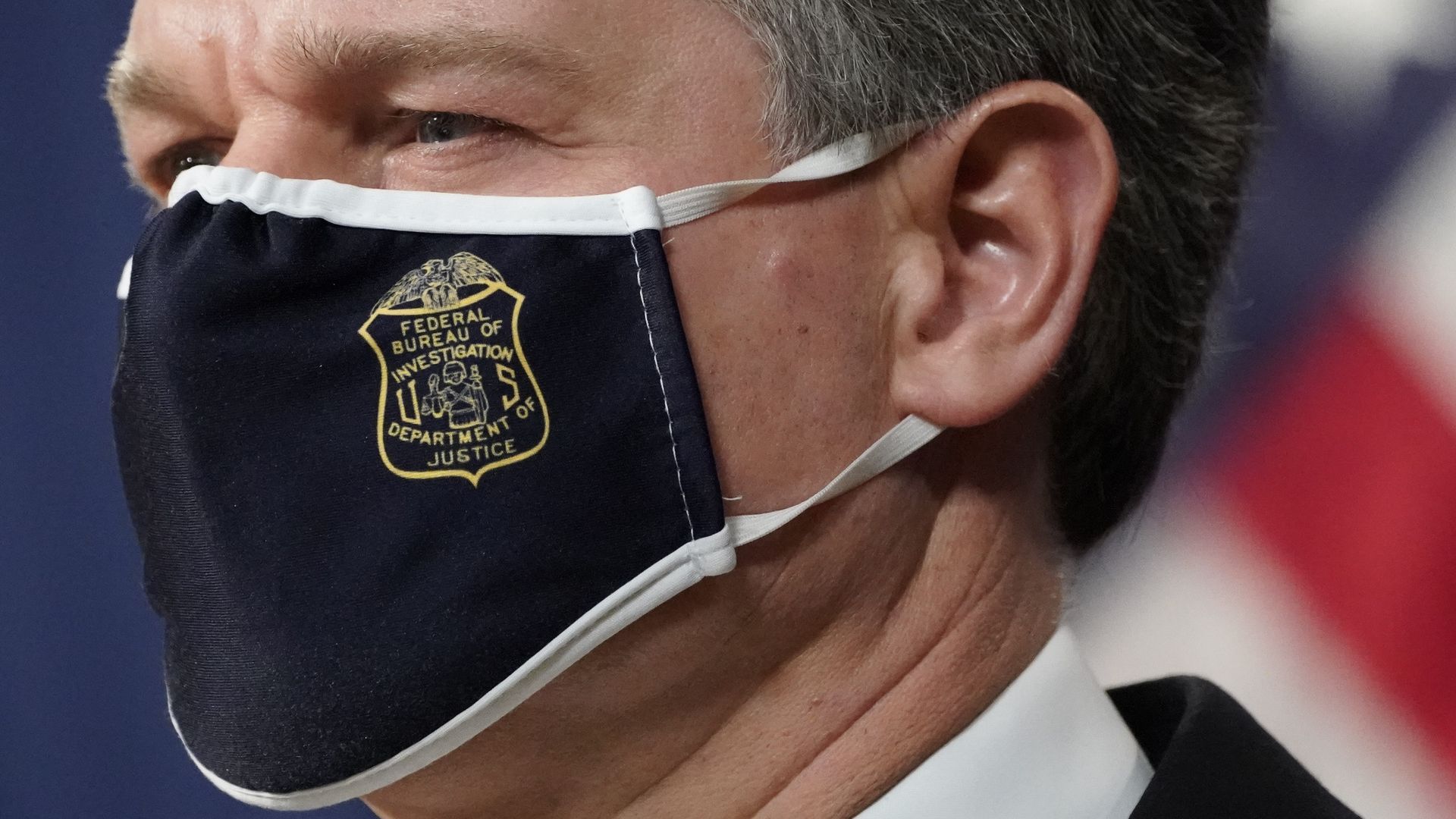 FBI Director Christopher Wray is seen wearing a mask emblazoned with the FBI logo during a news conference on Monday.
