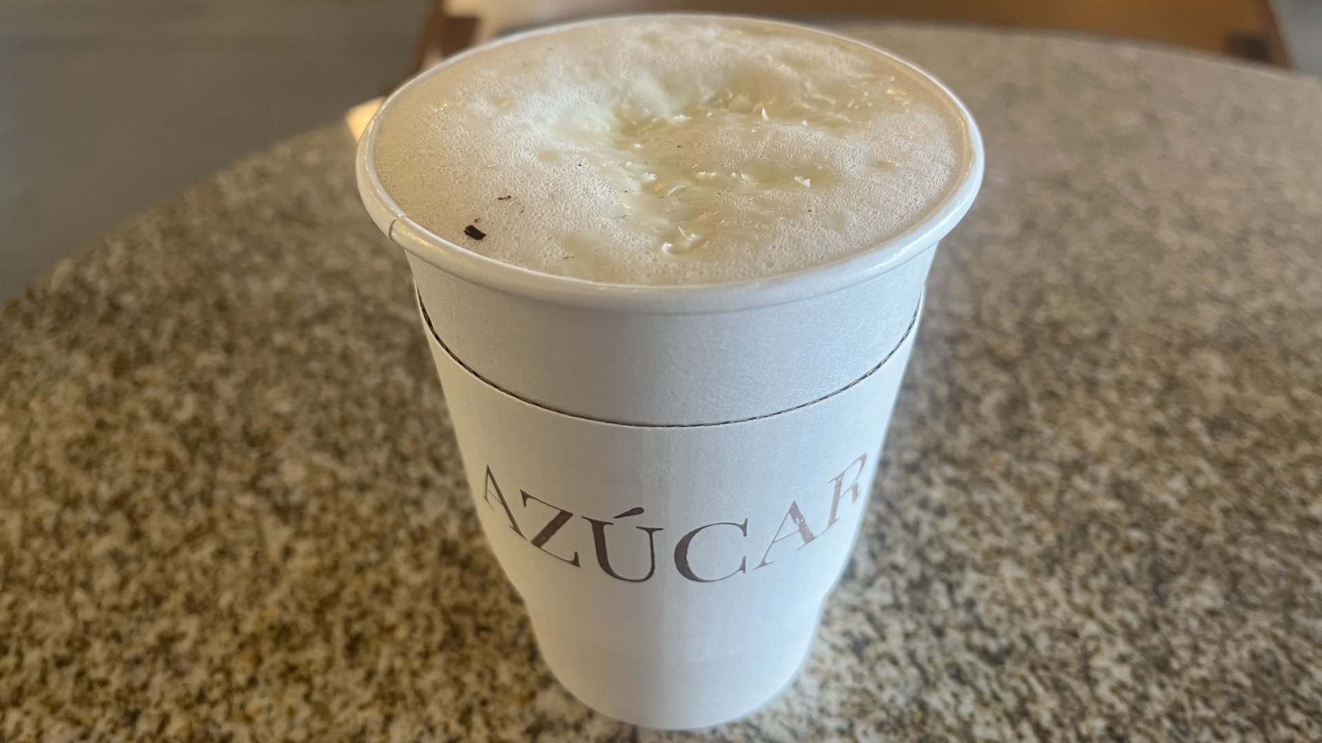 A to-go cup of coffee with "Azúcar" written on the sleeve.