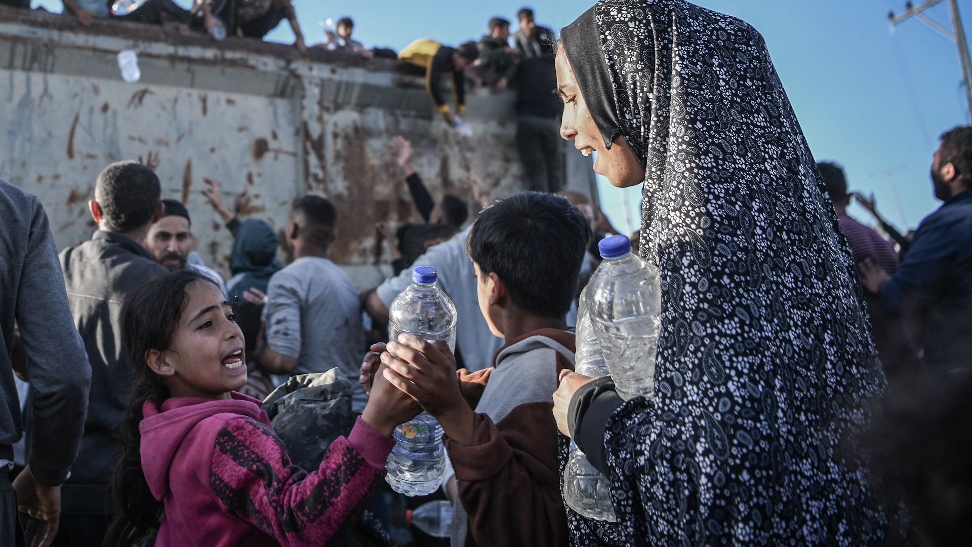 Palestinians flock to a truck carrying drinkable water