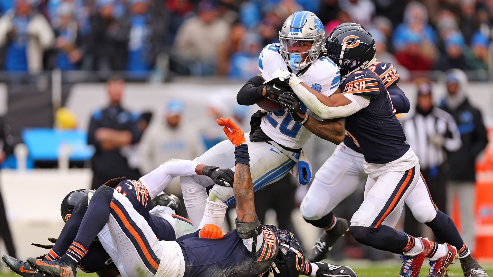 Jahmyr Gibbs #26 of the Detroit Lions is tackled by Jaquan Brisker #9 and Kyler Gordon #6 of the Chicago Bears during the third quarter at Soldier Field on December 10, 2023 in Chicago, Illinois. Photo by Michael Reaves/Getty