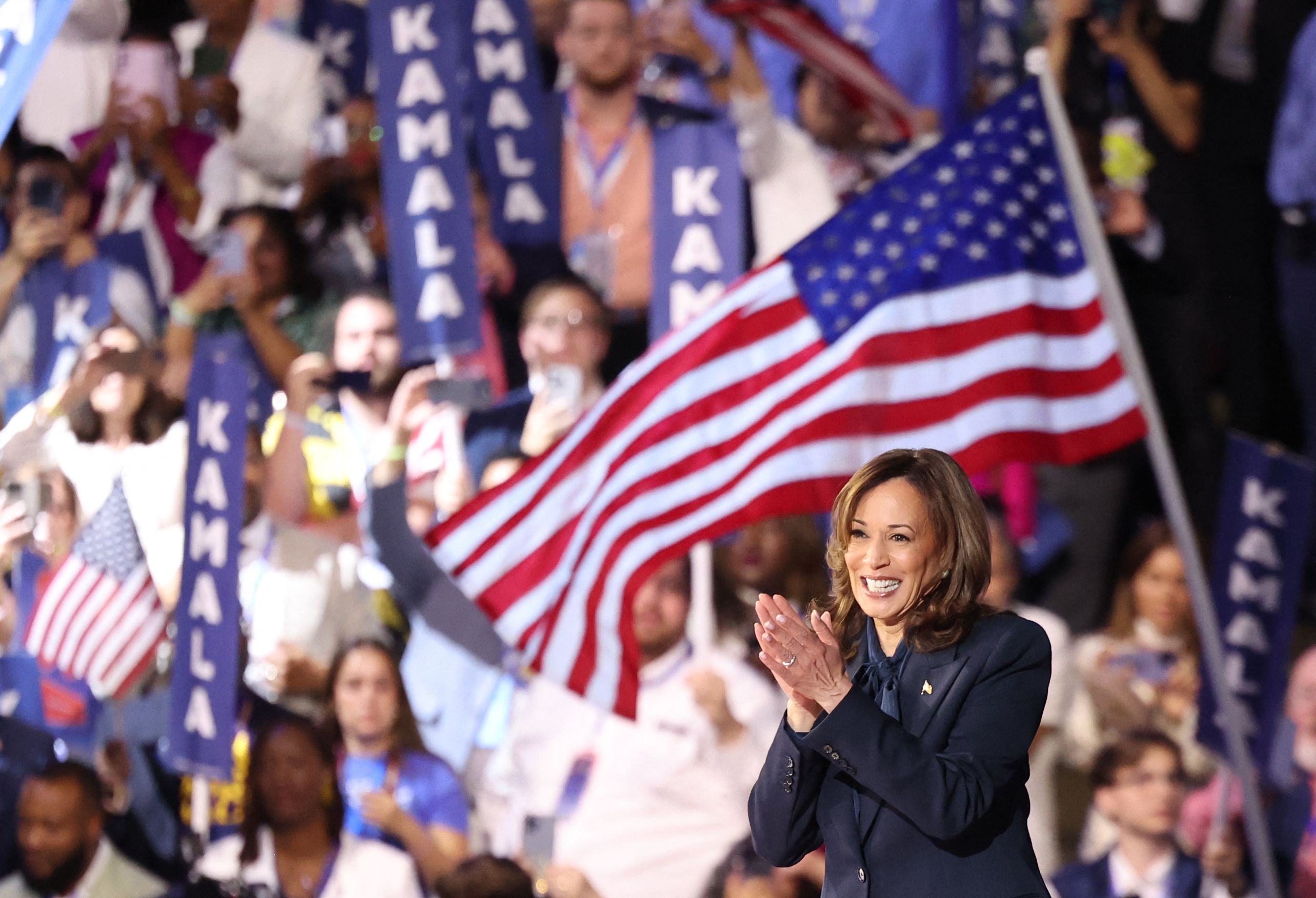 Harris stands with an American flag behind her on stage at the DNC