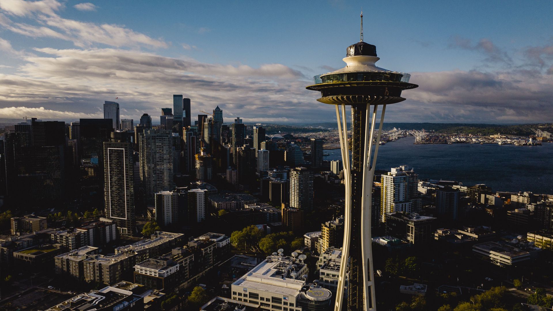 The Space Needle is shown in the foreground with the Seattle skyline and part of Elliott Bay behind it.