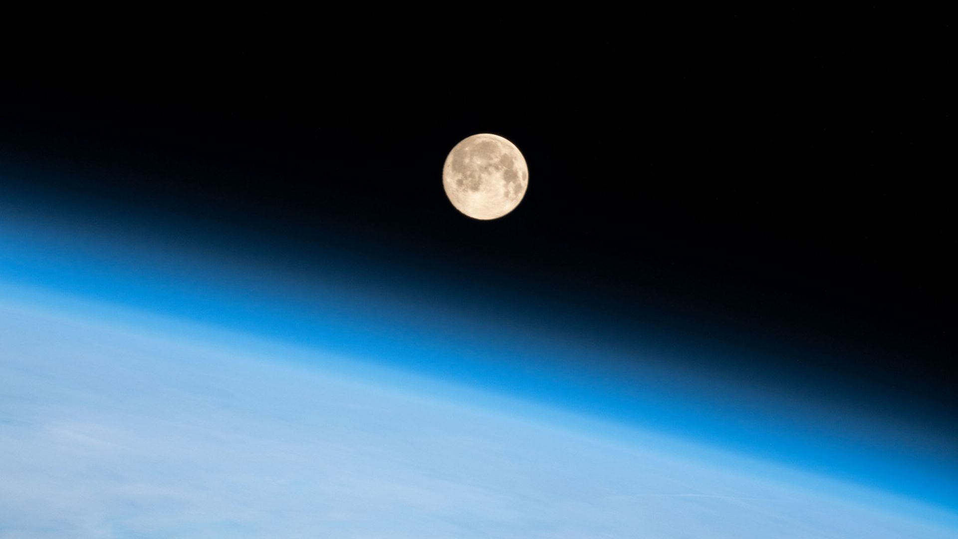 The Moon hovering above the blue limb of the Earth