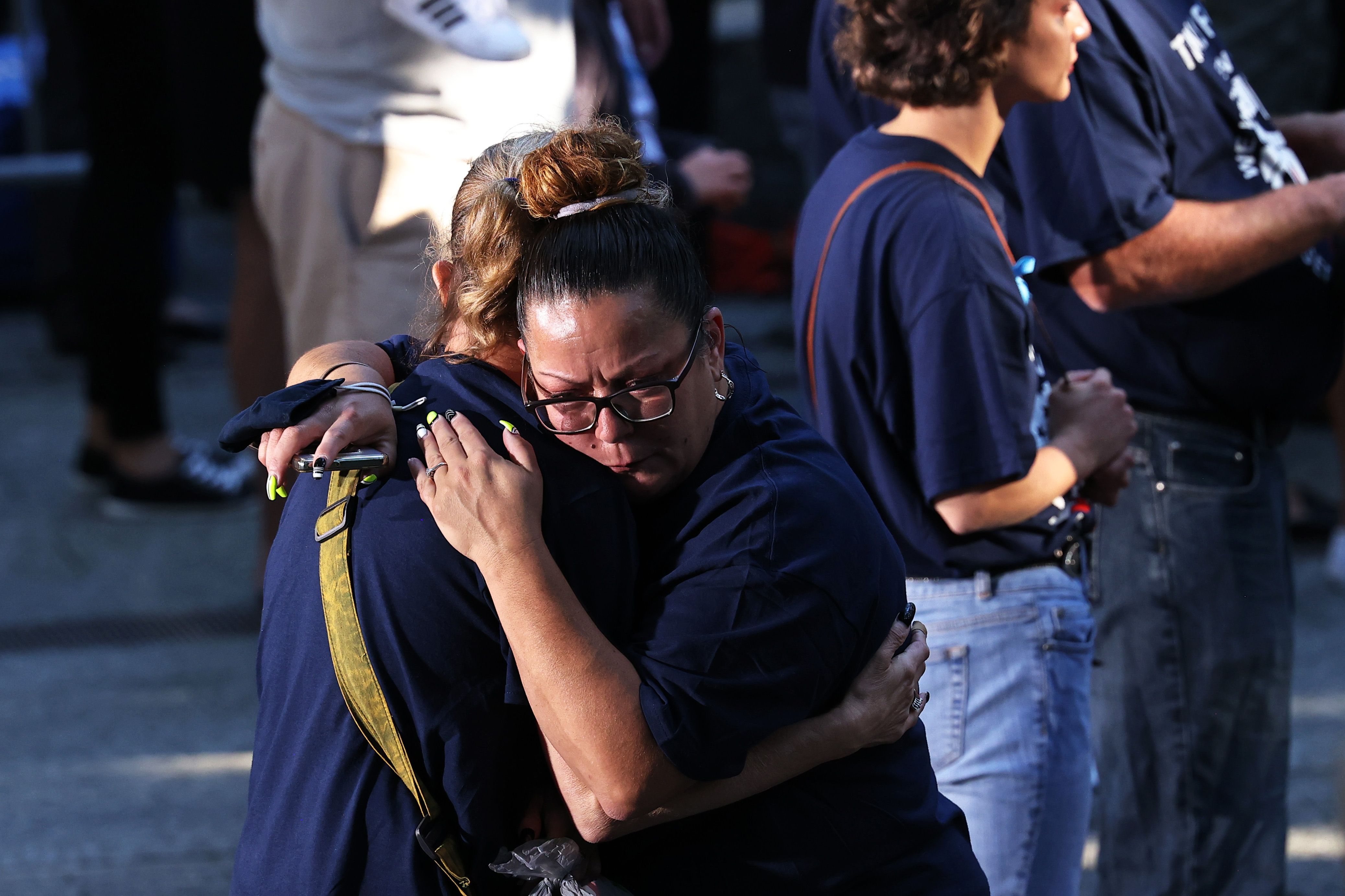 People embrace during the annual 9/11 Commemoration Ceremony at the National 9/11 Memorial and Museum