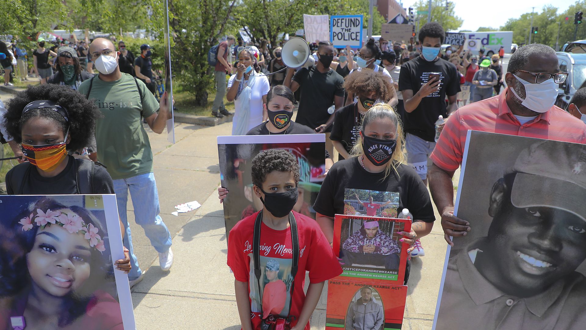 Masked protesters carry signs with