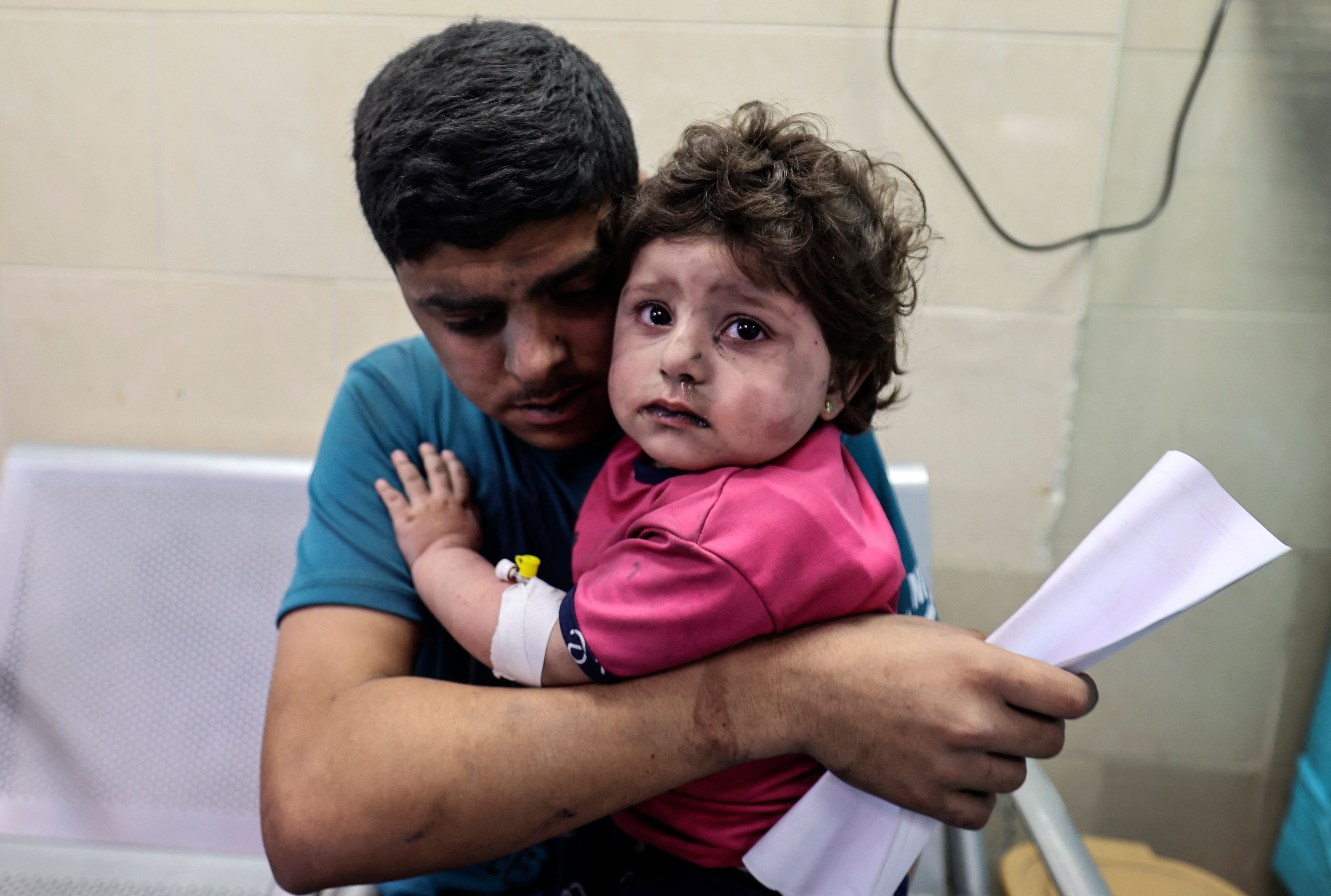 A Palestinian man holds an injured girl awaiting medical care at al-Shifa hospital, after an Israeli air strike in Gaza city, on May 11