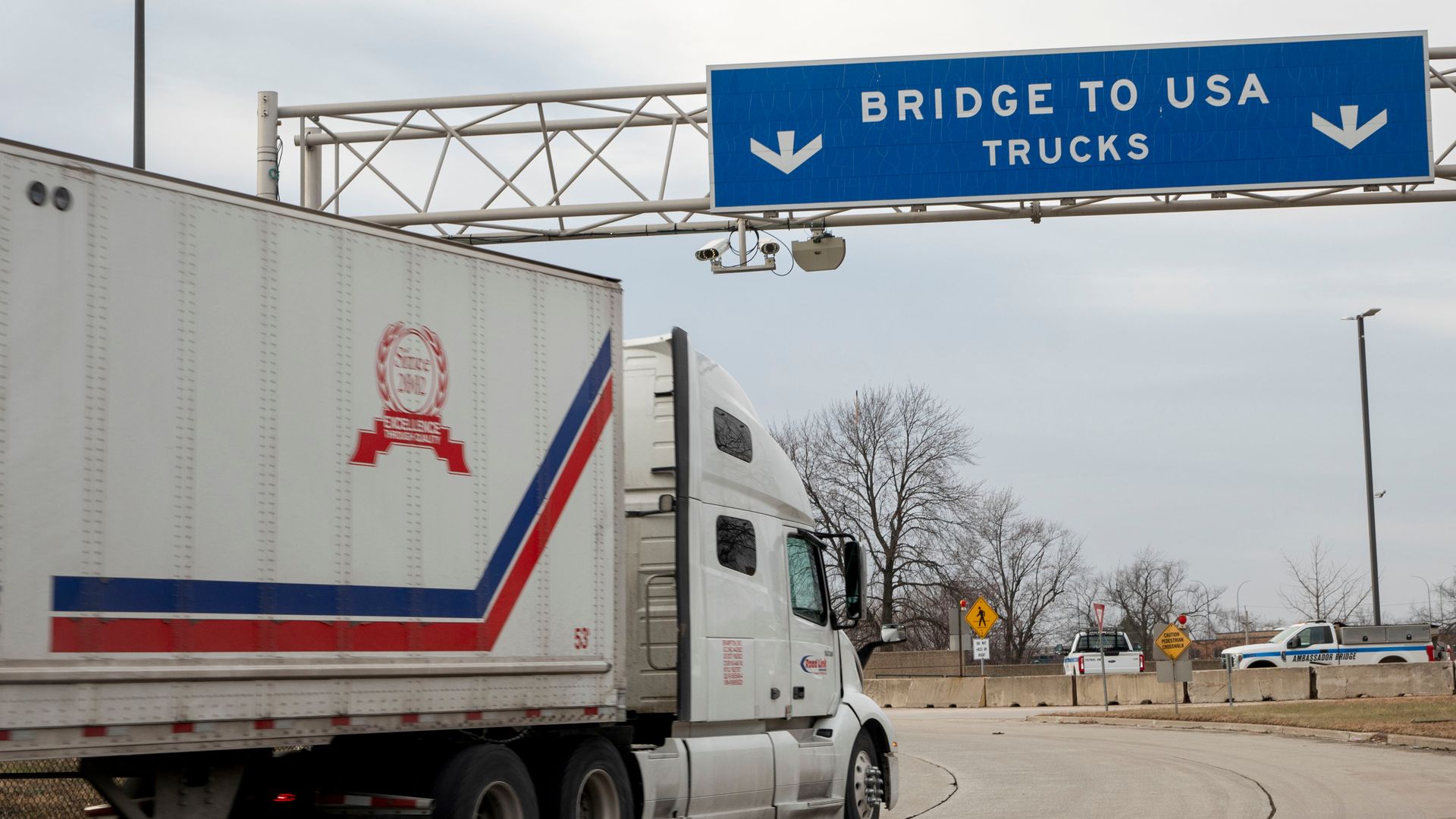 A truck entering the United States, passing under a "Bridge to USA" sign.