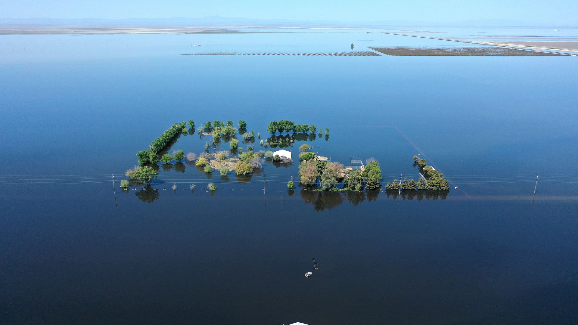 Aerial image of a home and farmlands surrounded by floodwaters in Corcoran, California in April 2023.