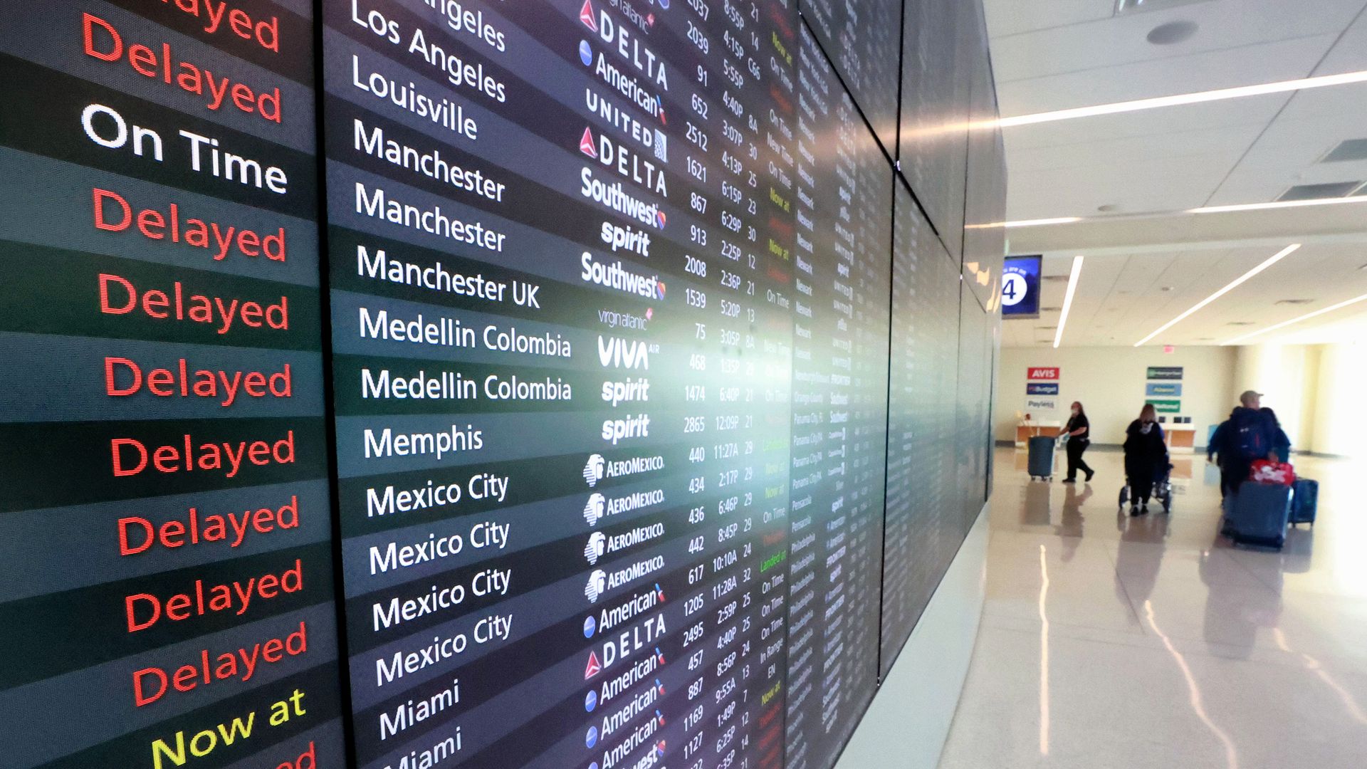 A list of delayed and canceled flights on a screen at an airport.