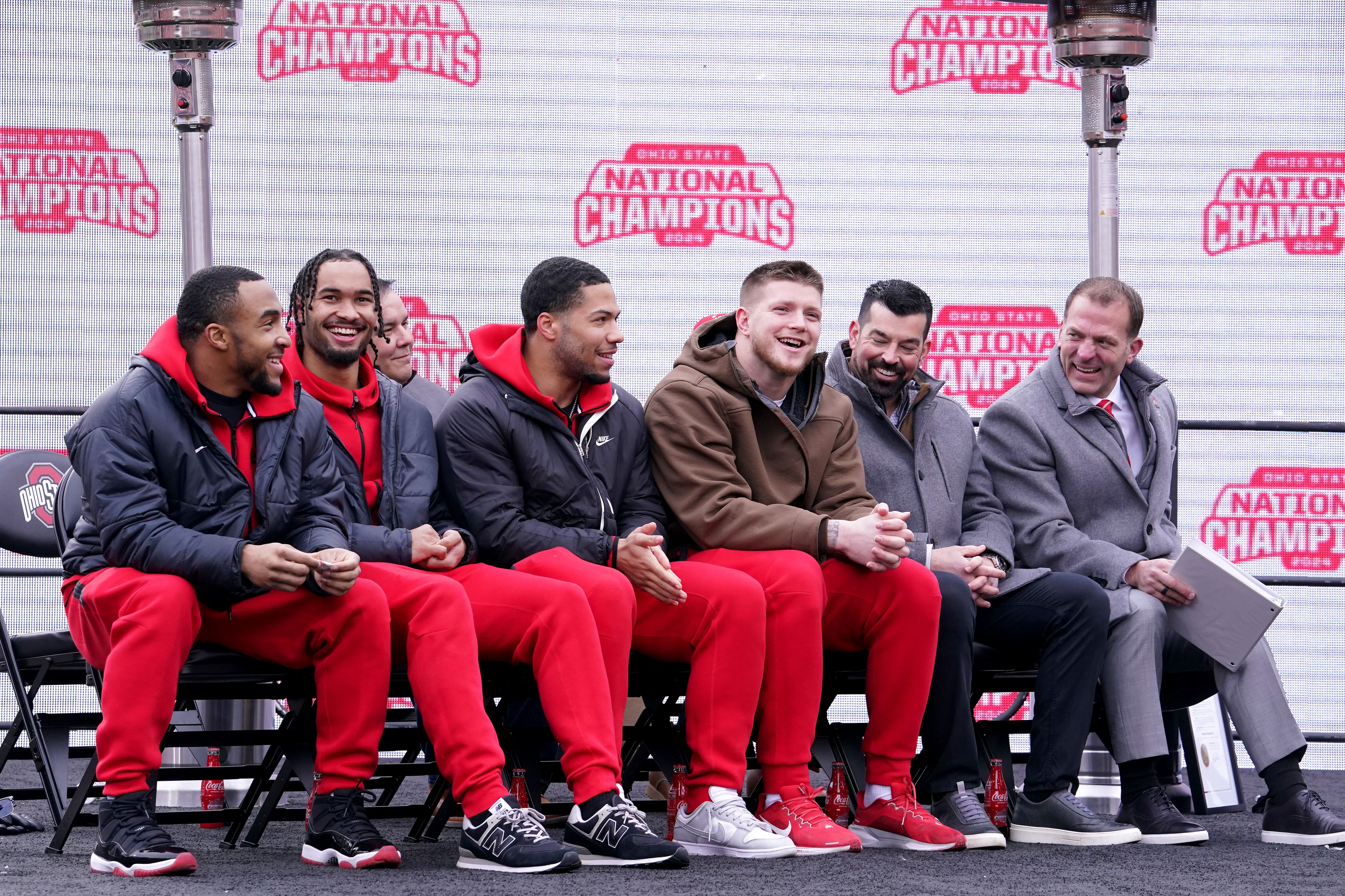 From left, running back TreVeyon Henderson, wide receiver Emeka Egbuka, linebacker Cody Simon, defensive end Jack Sawyer, head coach Ryan Day and OSU athletics director Ross Bjork sit together during Sunday's celebration and laugh