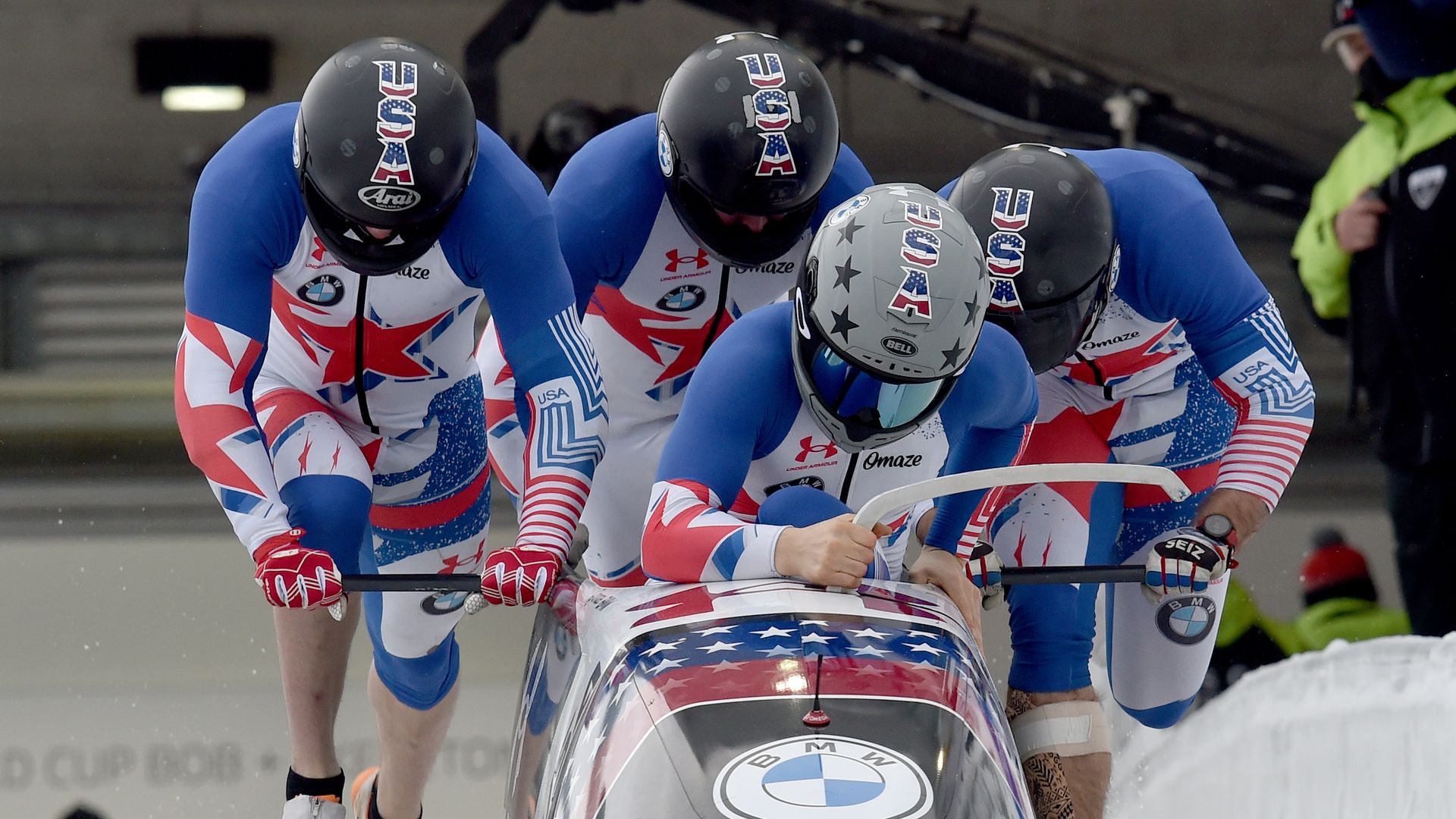 A photo of four people pushing a bobsled.