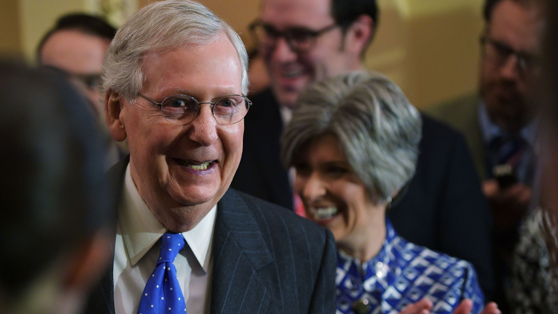 Mitch McConnell grins, surrounded by Republican senators