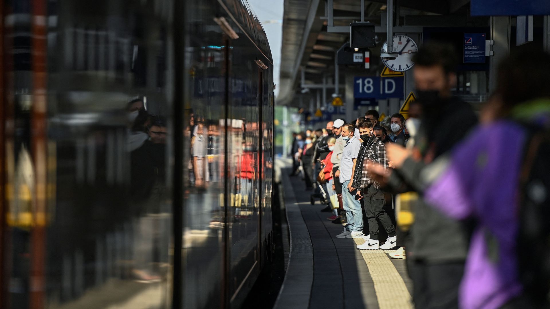 Travellers stand on a platform where a local train is arriving at the main railway station in Dortmund on June 1, 2022
