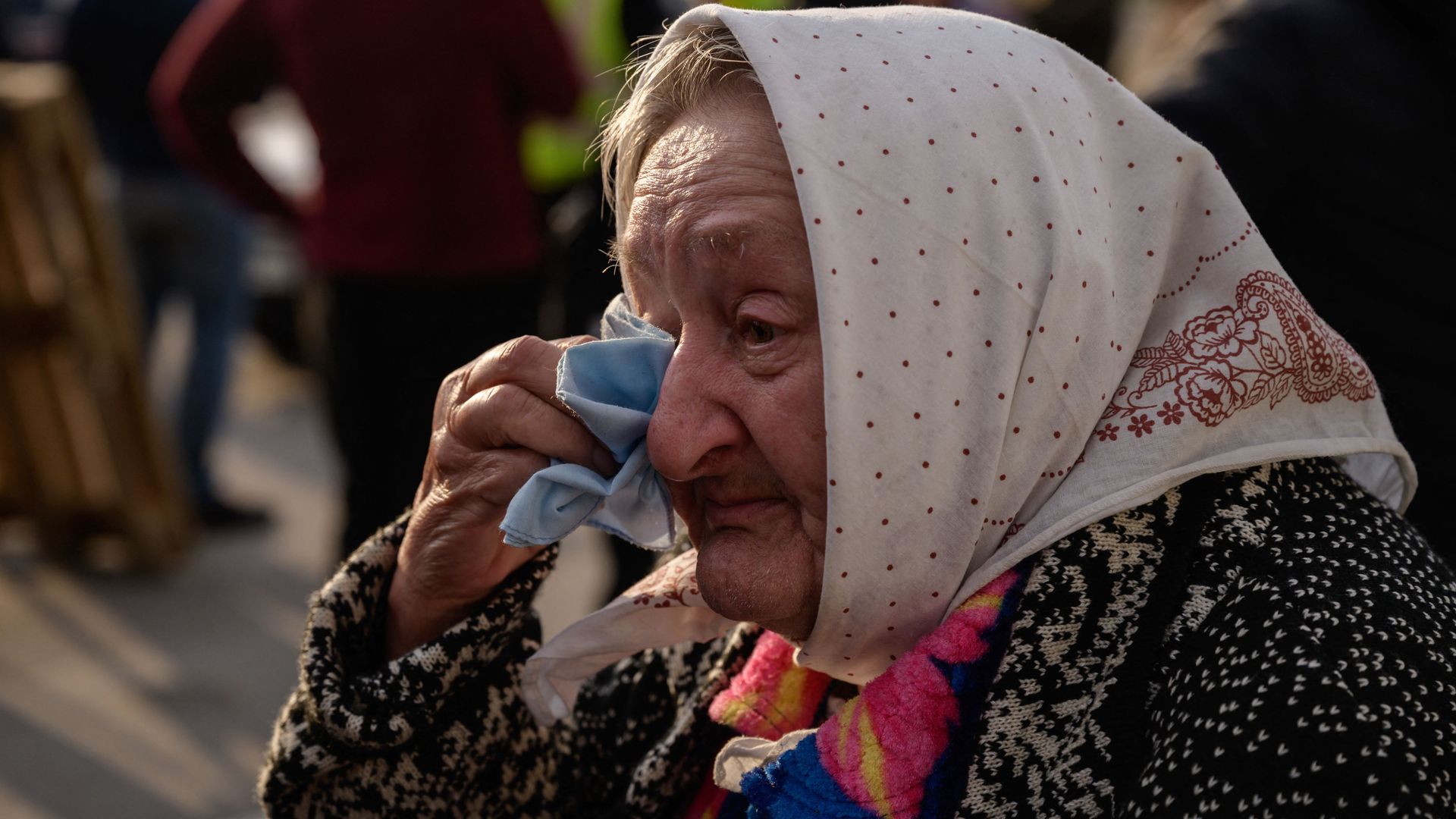 A woman who fled the besieged city of Mariupol reacts as she arrives in a private vehicle at a registration and processing area for internally displaced people in Zaporizhzhia