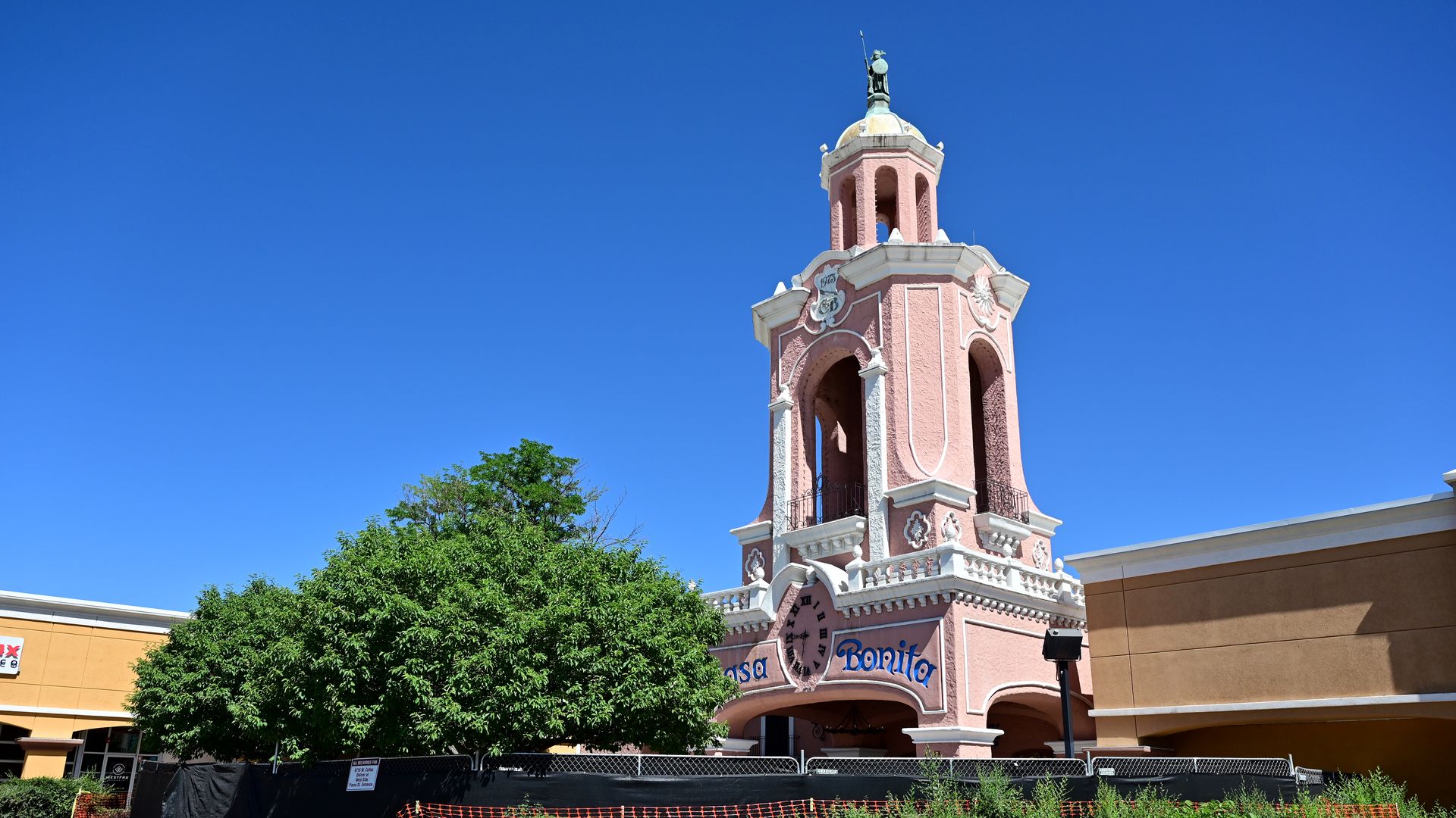 A pink, cathedral-like structure tower looms over a suburban shopping complex. 
