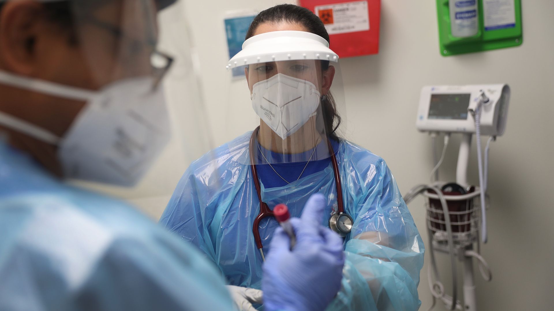 A woman wearing a face mask, face shield and other protective gear