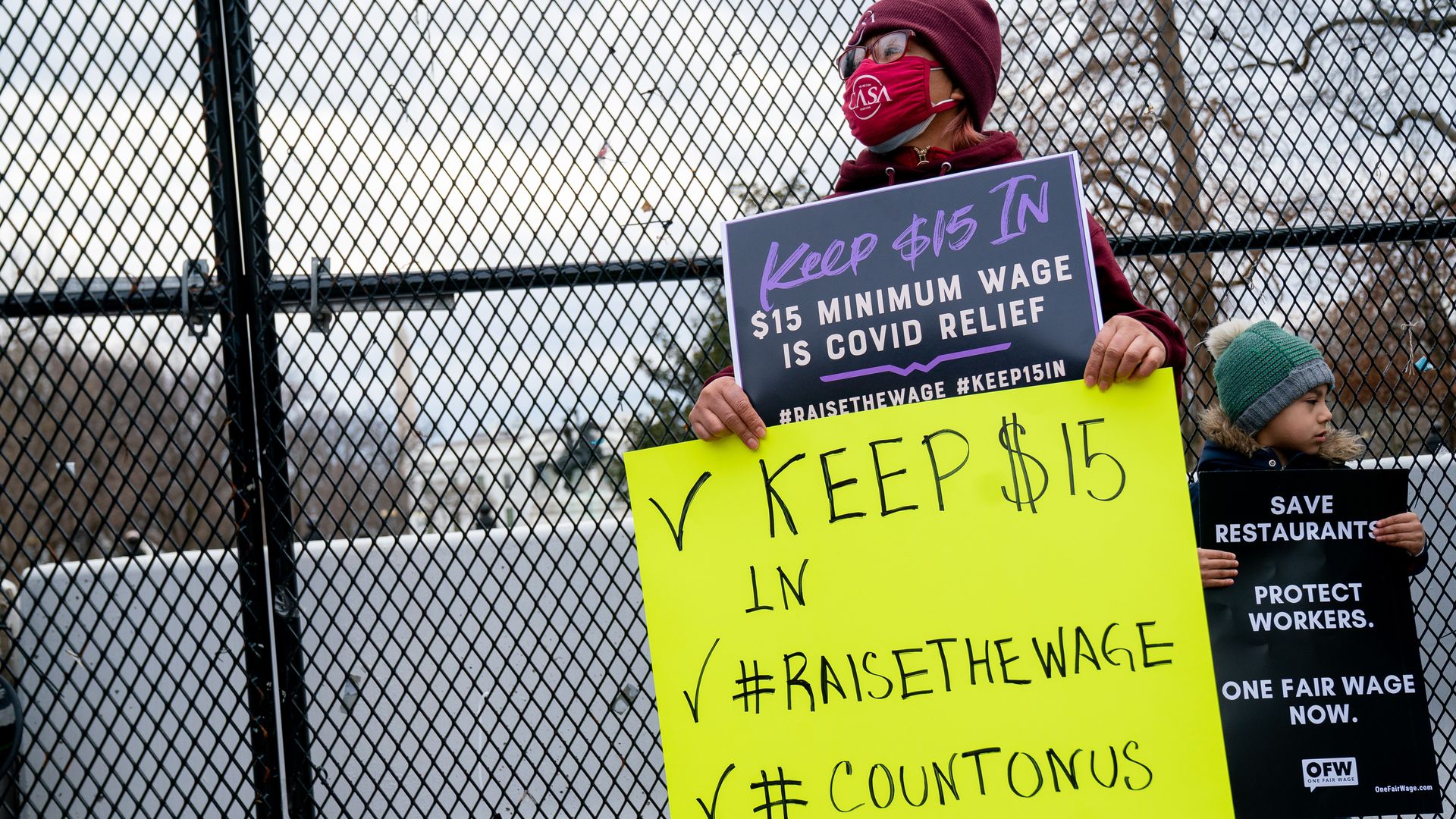 A photo of a protester with a sign supporting a $15 an hour minimum wage.