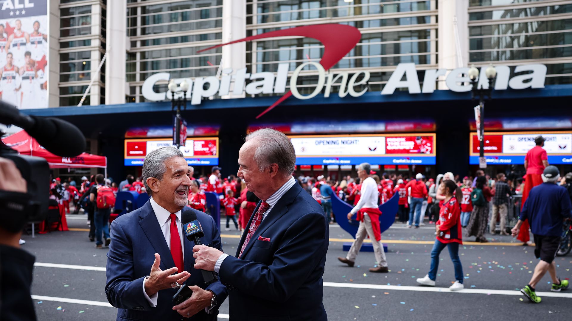 An exterior photograph of the Capital One Arena in D.C., home of the Washington Capitals, with team owner Ted Leonsis standing out front talking to a TV commentator.