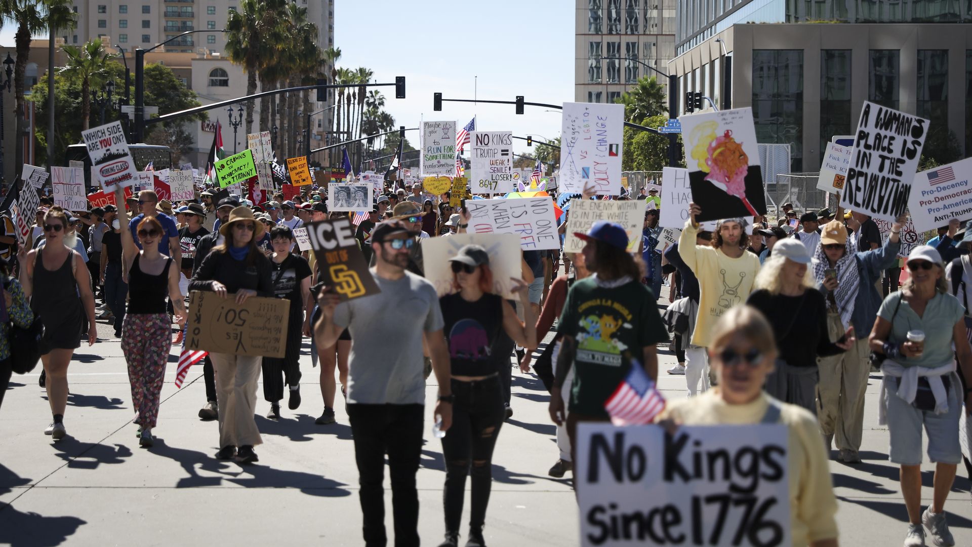 A crowd of people holding signs stands in the street for the San Diego No Kings protest on Saturday, Oct. 18, 2025.