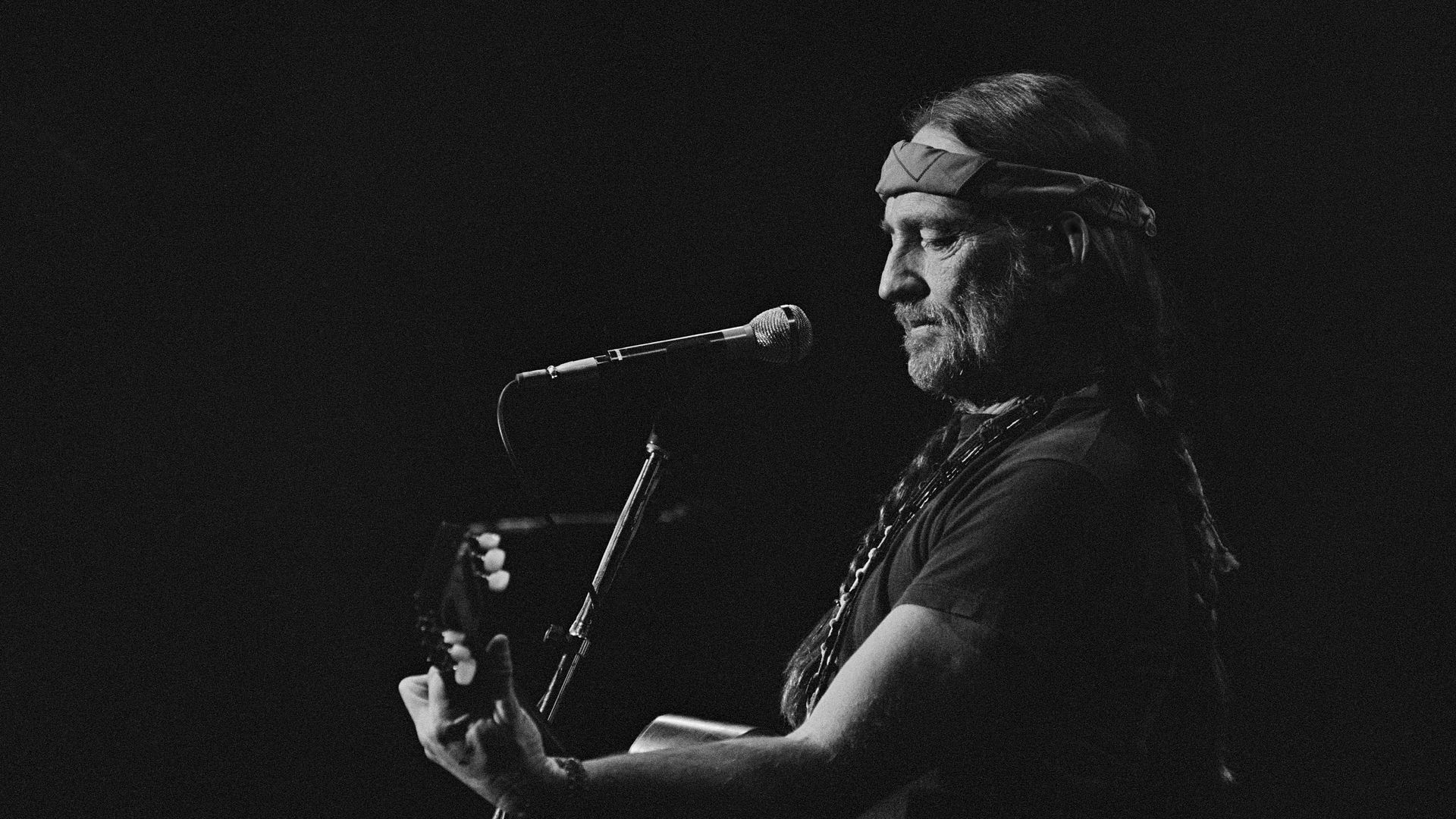 Willie Nelson playing his guitar.