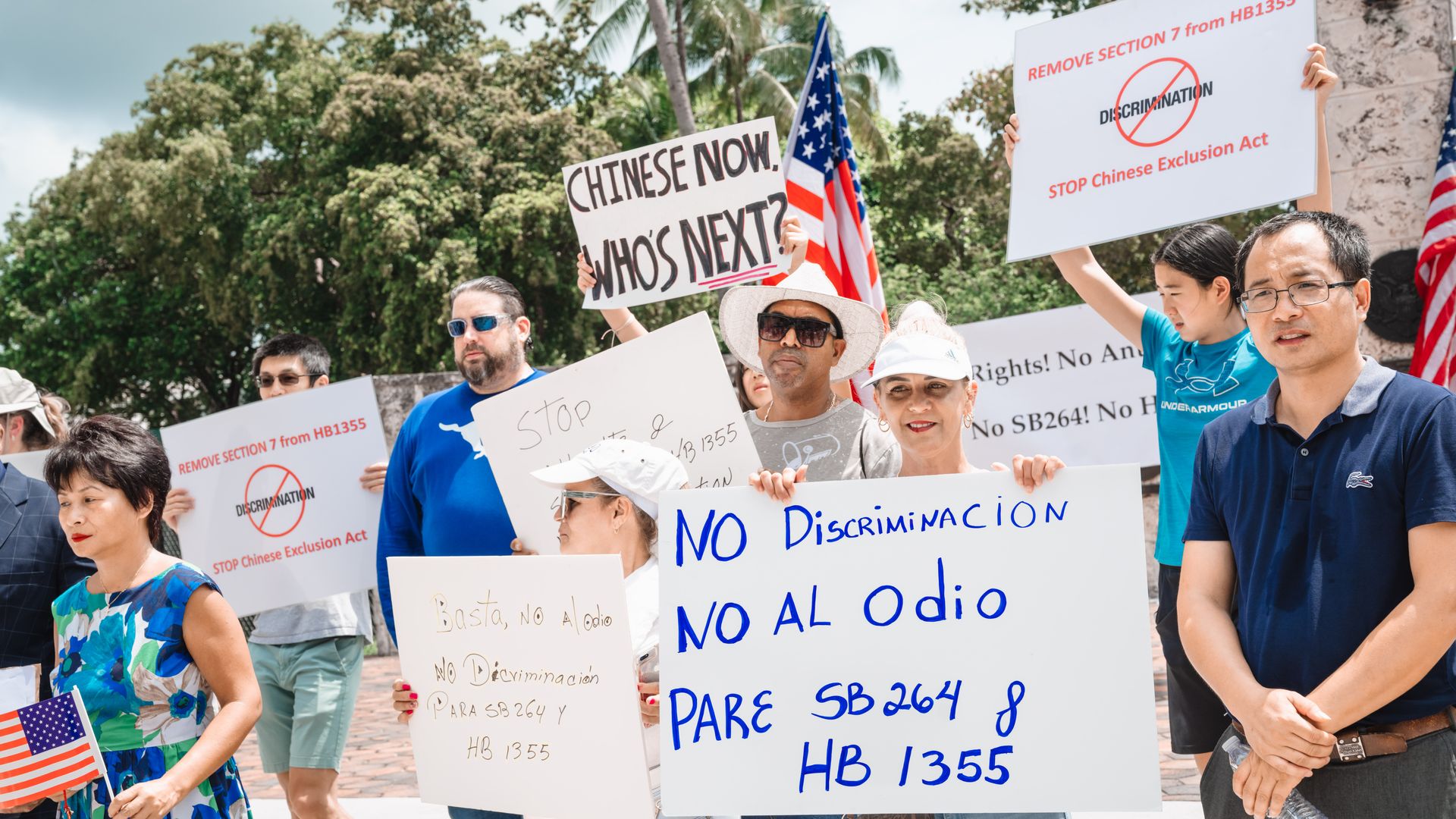 A group of protestors holds signs and waves flags 