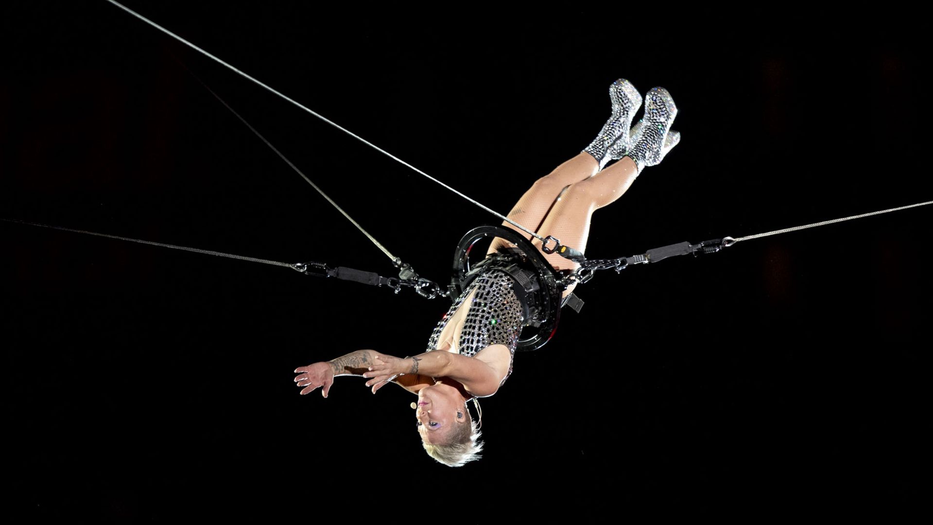 The singer Pink is suspended upside down from trapeze wires during a concert