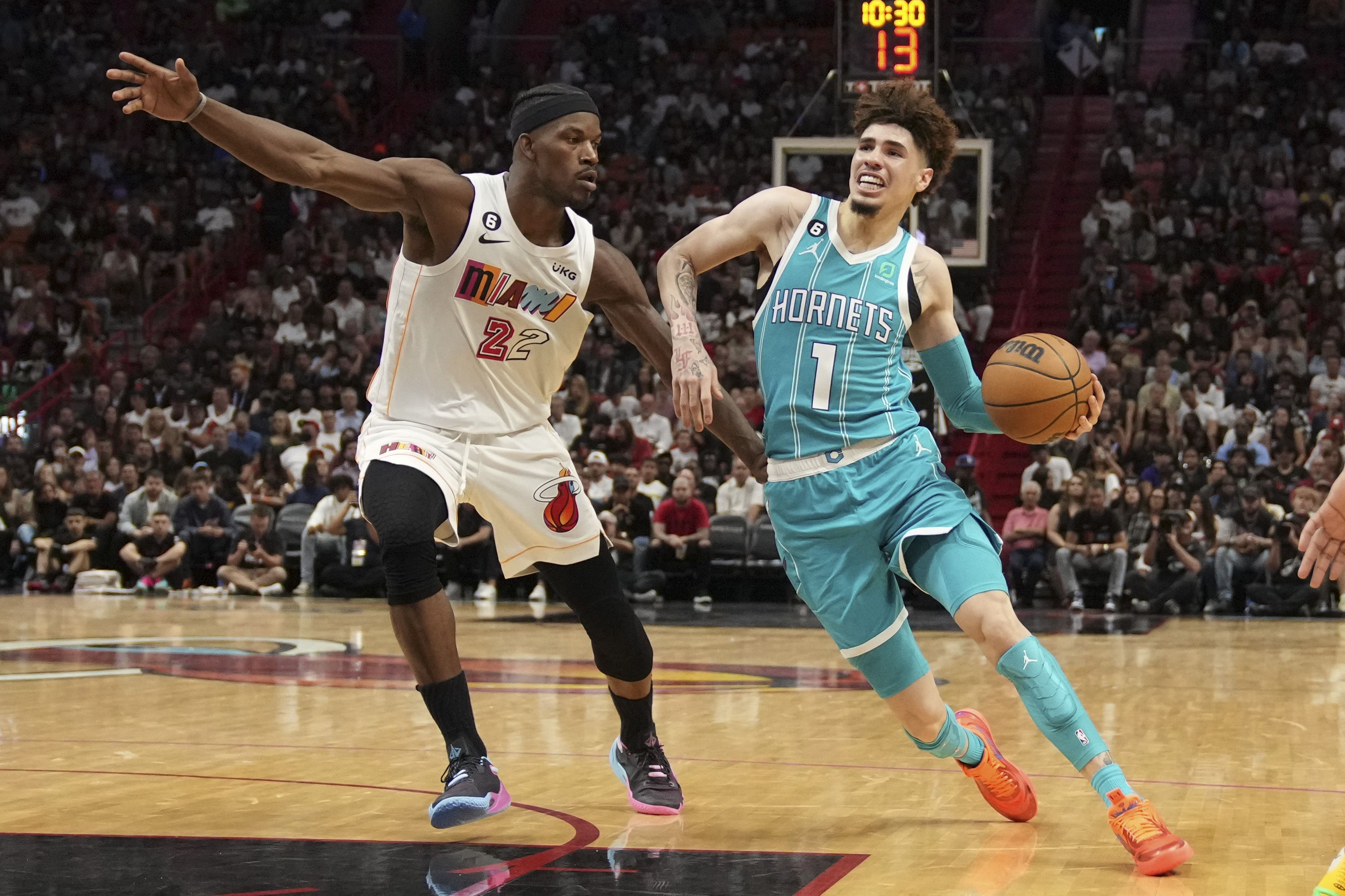  LaMelo Ball #1 of the Charlotte Hornets drives to the basket while being defended by Jimmy Butler #22 of the Miami Heat during Saturday's game.
